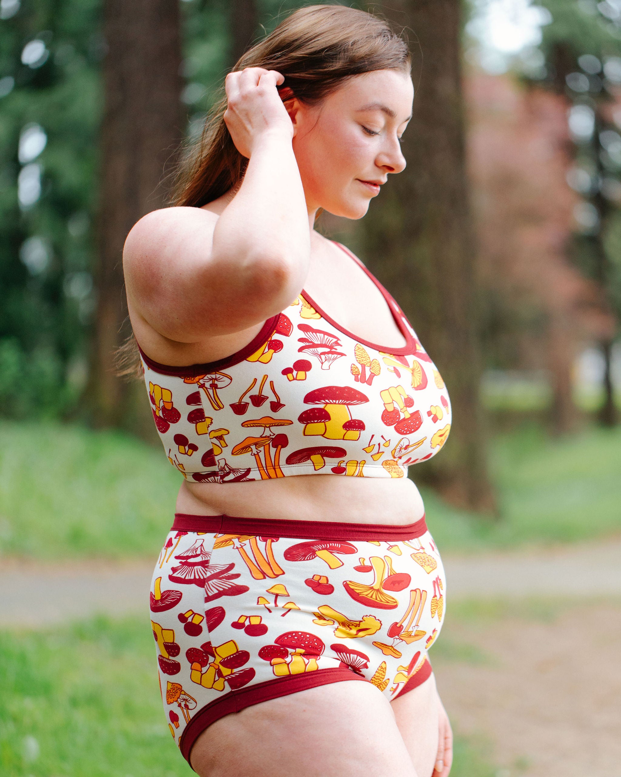 Model wearing Thunderpants Sky Rise style underwear and Bralette in Whadda Fungi print - red, yellow, and orange mushroom print.