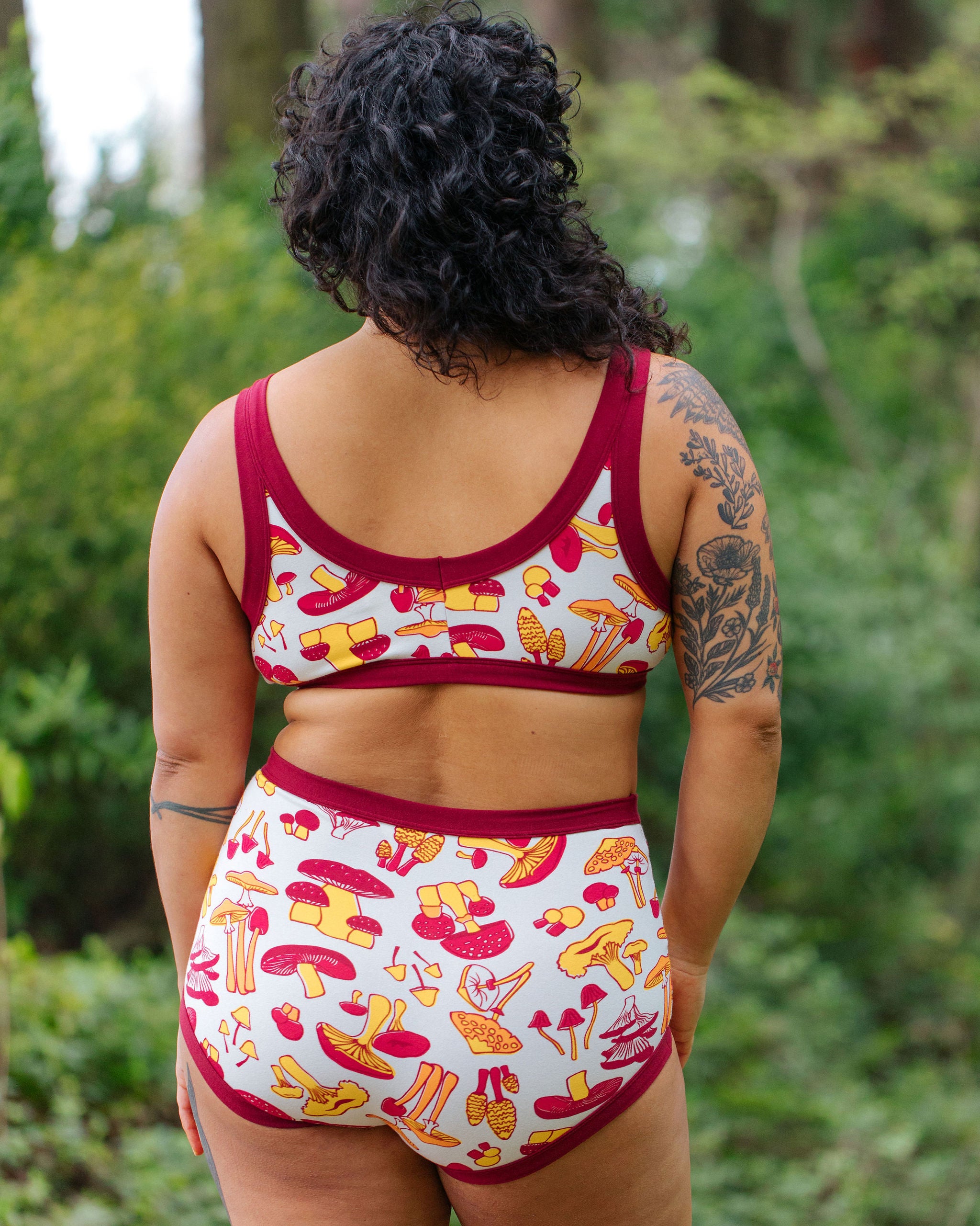 Model wearing Thunderpants Sky Rise style underwear and Bralette in Whadda Fungi print - red, yellow, and orange mushroom print.