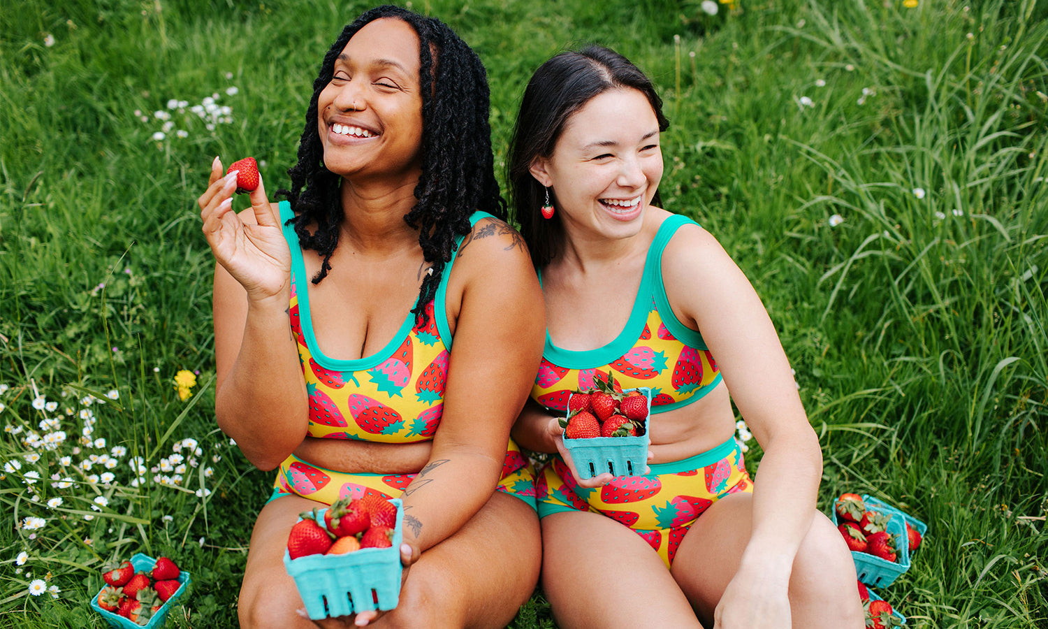 Two models smiling while wearing sets in Thunderpants Strictly Strawberry print - pink, red, and peacock green.