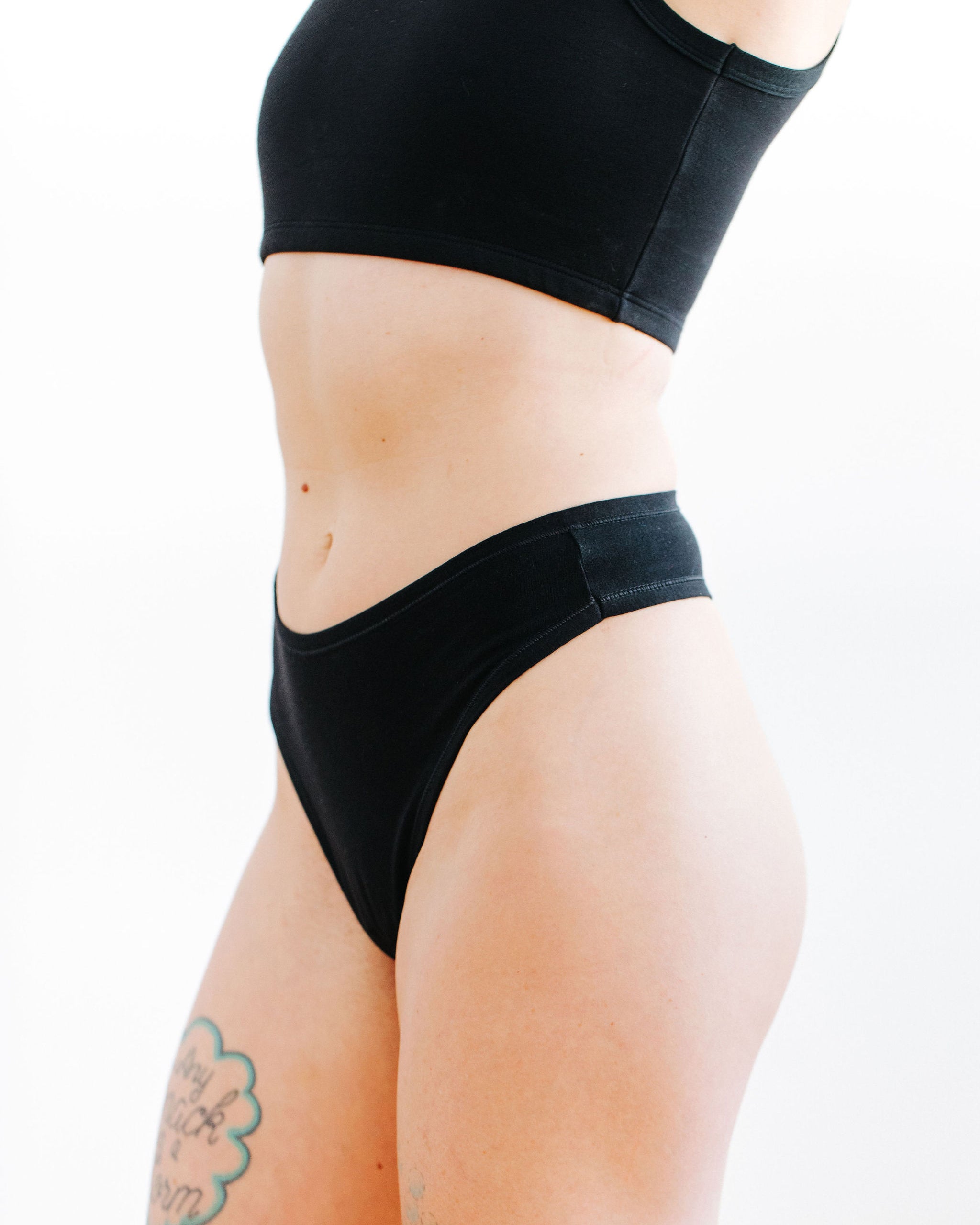 Close up of model wearing Thunderpants Thong style underwear and Long Line Bra in Plain Black.