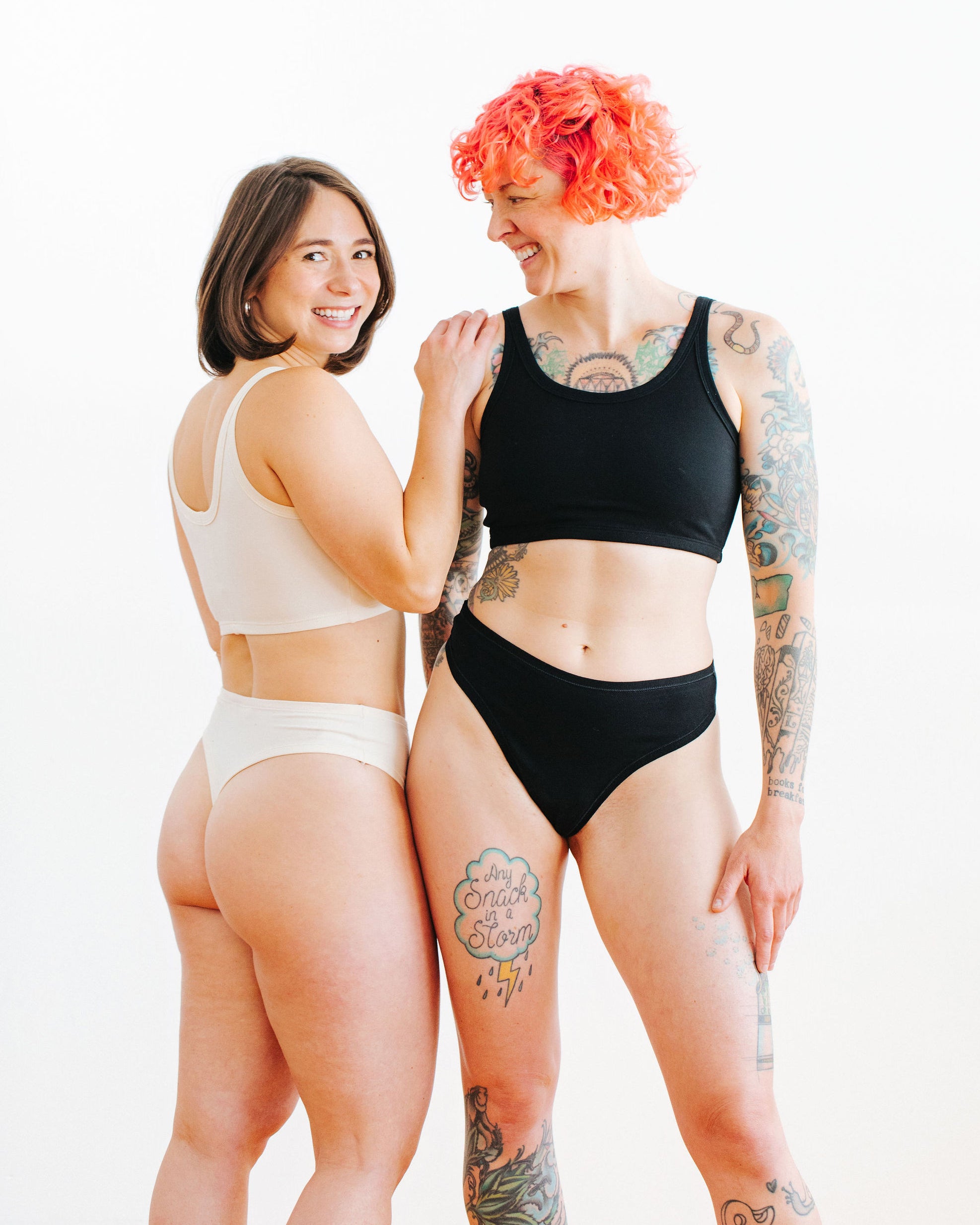 Two models wearing Thunderpants Thong style underwear and Long Line Bra in Plain Black and Plain Vanilla.