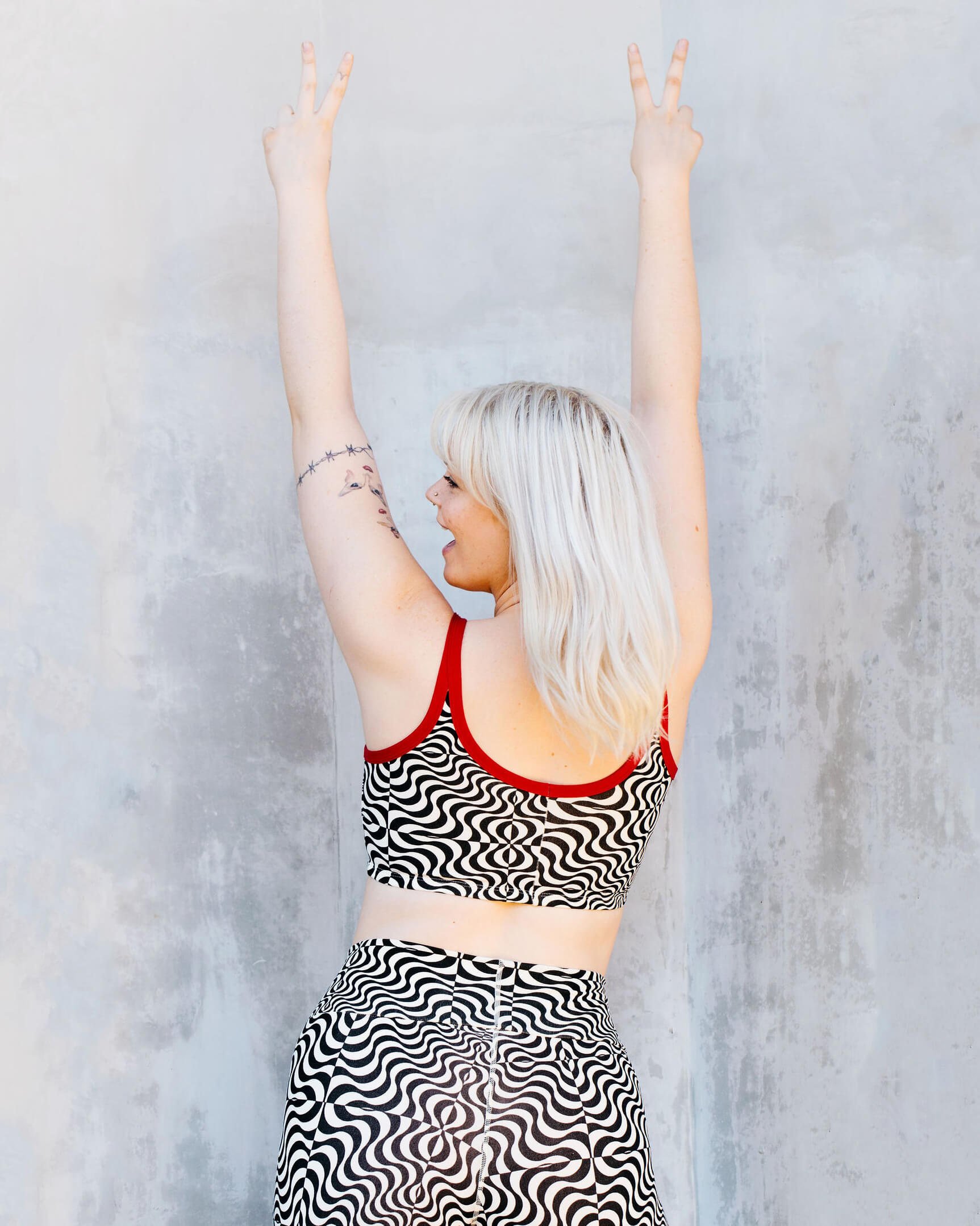 Close up of model wearing Thunderpants longline bra in Tropical Trippy - black and vanilla squiggles with red binding.