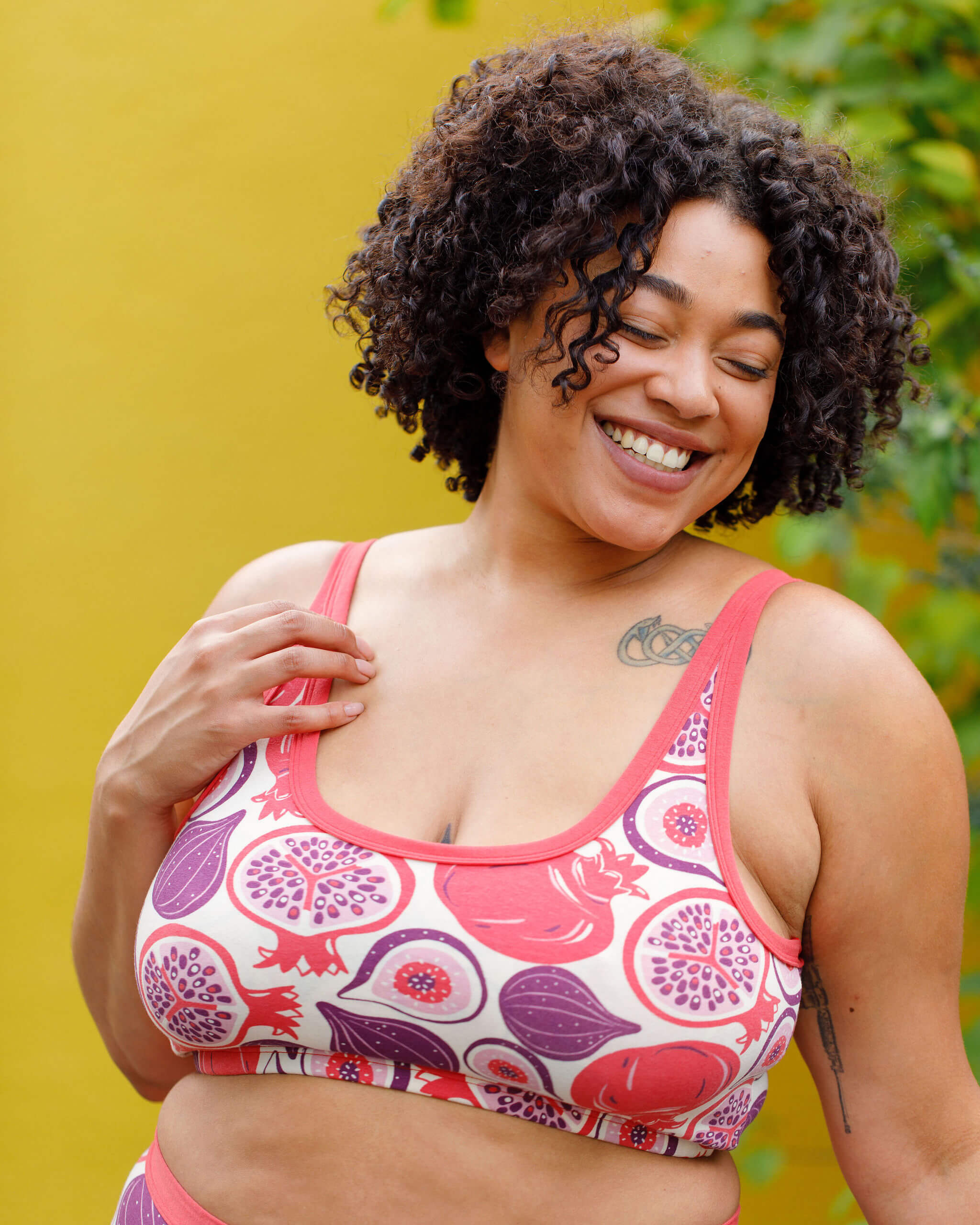 Close up of model wearing Thunderpants Longline Bra in Two Fruits - pomegranates and figs.