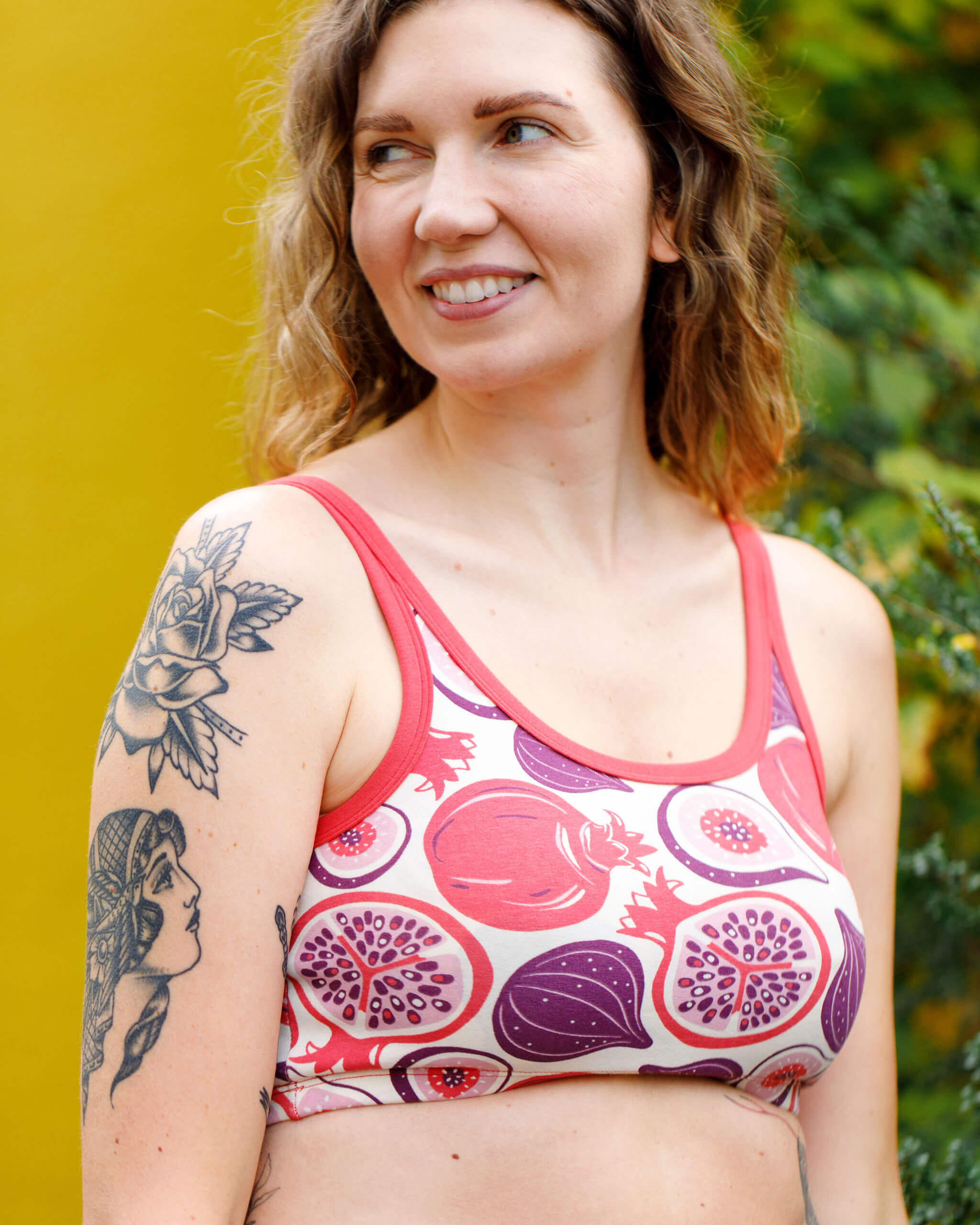 Close up of model wearing Thunderpants Longline Bra in Two Fruits - pomegranates and figs.