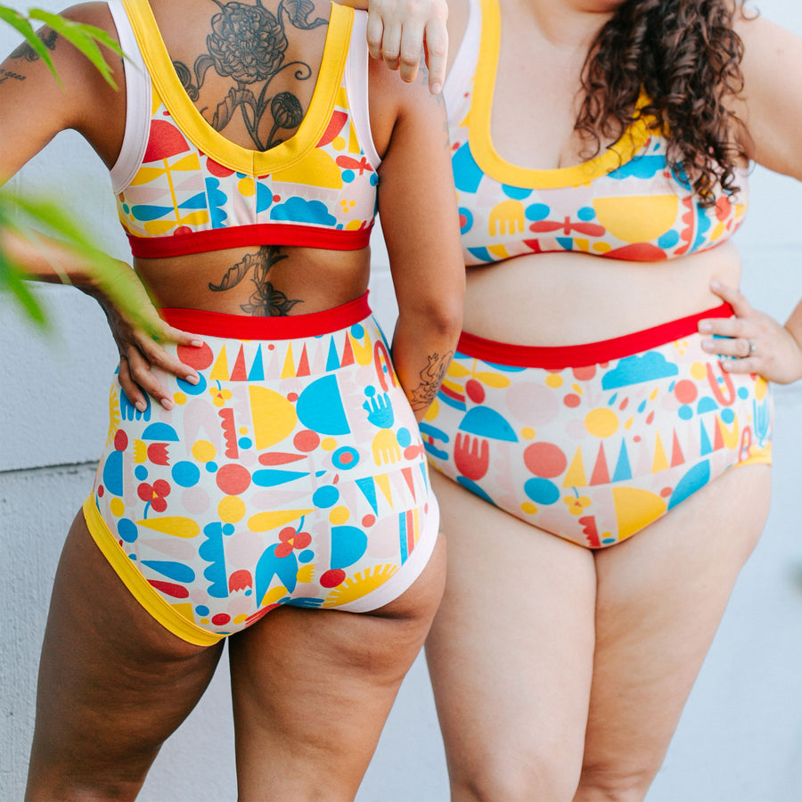 Two models wearing sets of Bralettes and underwear in Balance by Lisa Congdon print: geometric shapes in red, blue, pink, and yellow colors.
