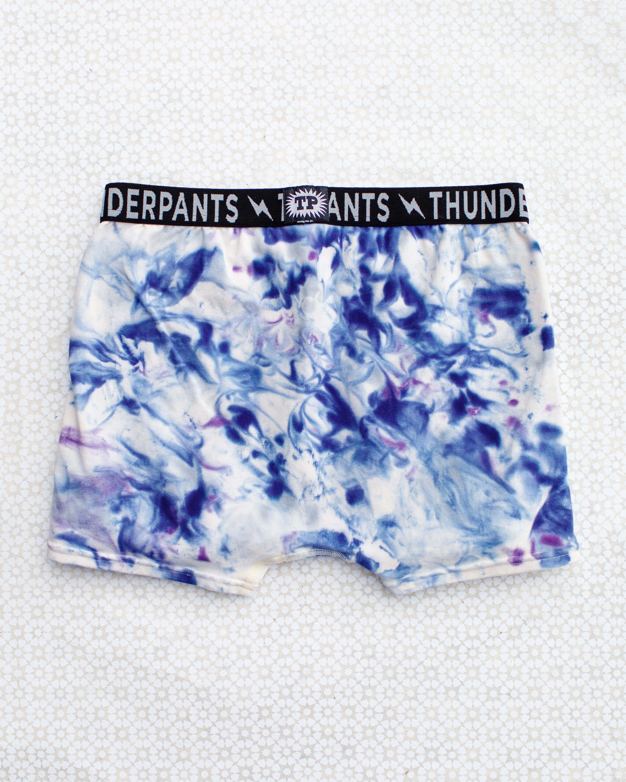 Flat lay of Thunderpants Boxer Brief style underwear in Winter Blues Marble dye - different blues and purples swirled to look like marble. 