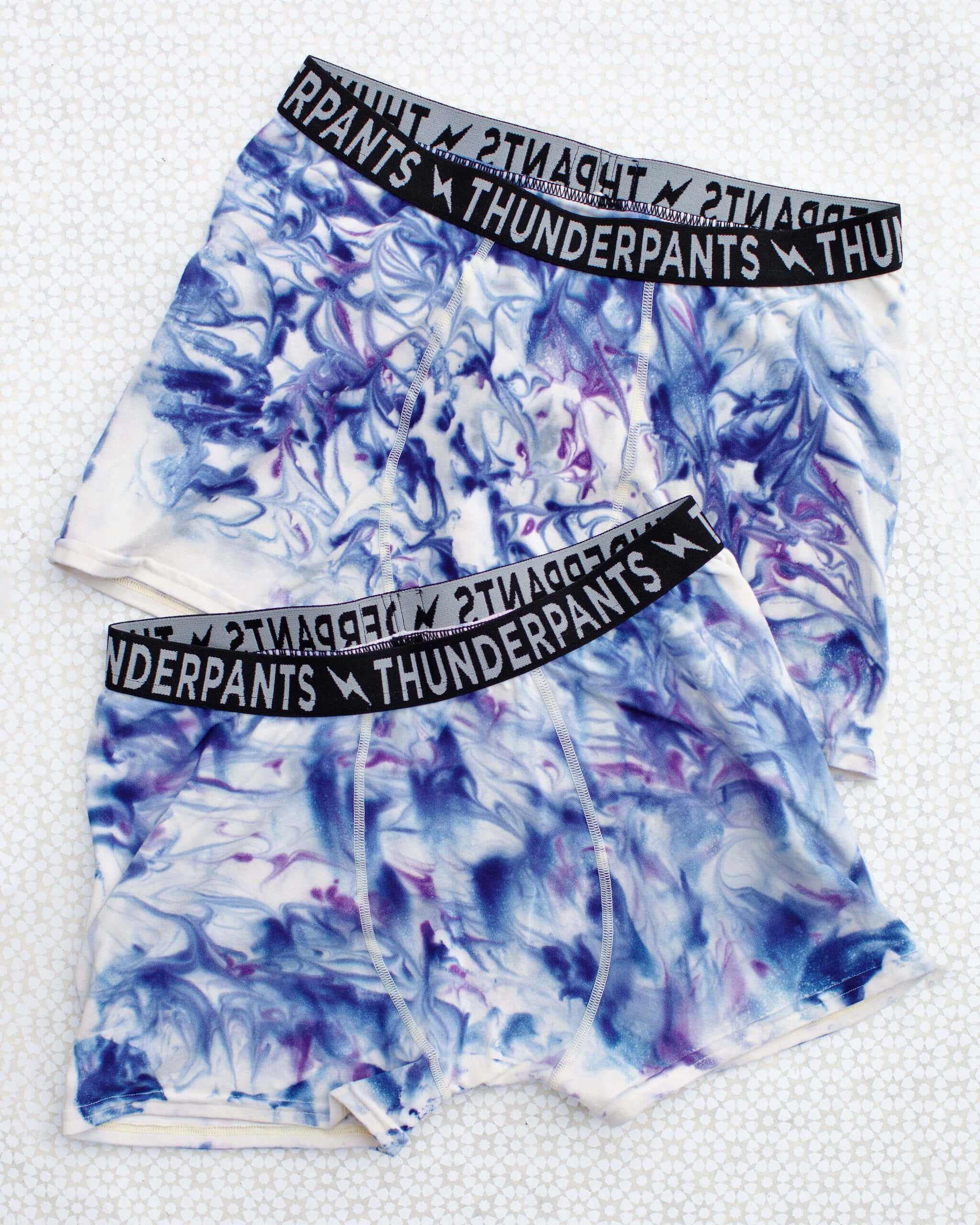 Flat lay of Thunderpants Boxer Brief style underwear in Winter Blues Marble dye - different blues and purples swirled to look like marble. 