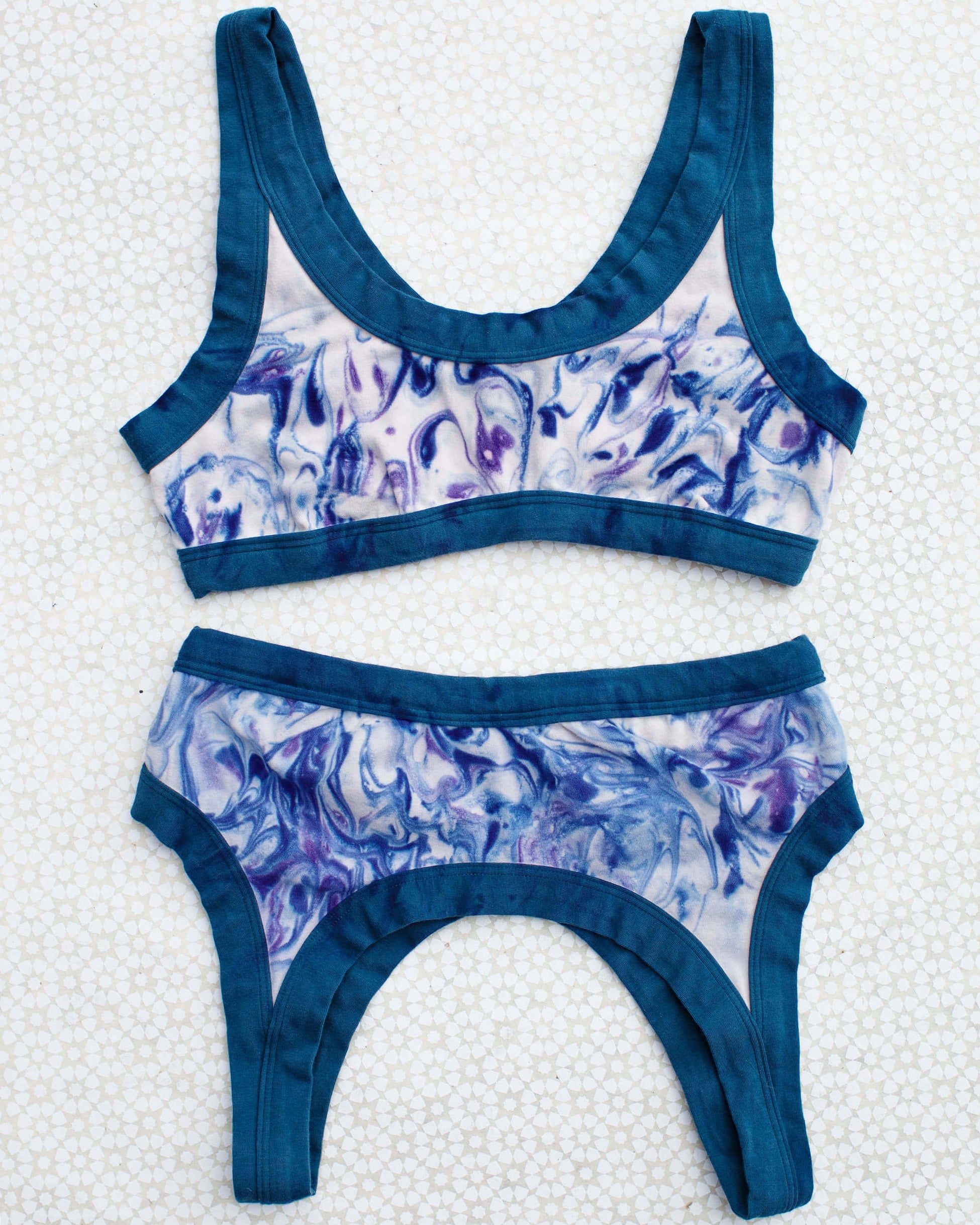 Flat lay of Thunderpants Bralette in Winter Blues Marble dye - different blues and purples swirled to look like marble. 