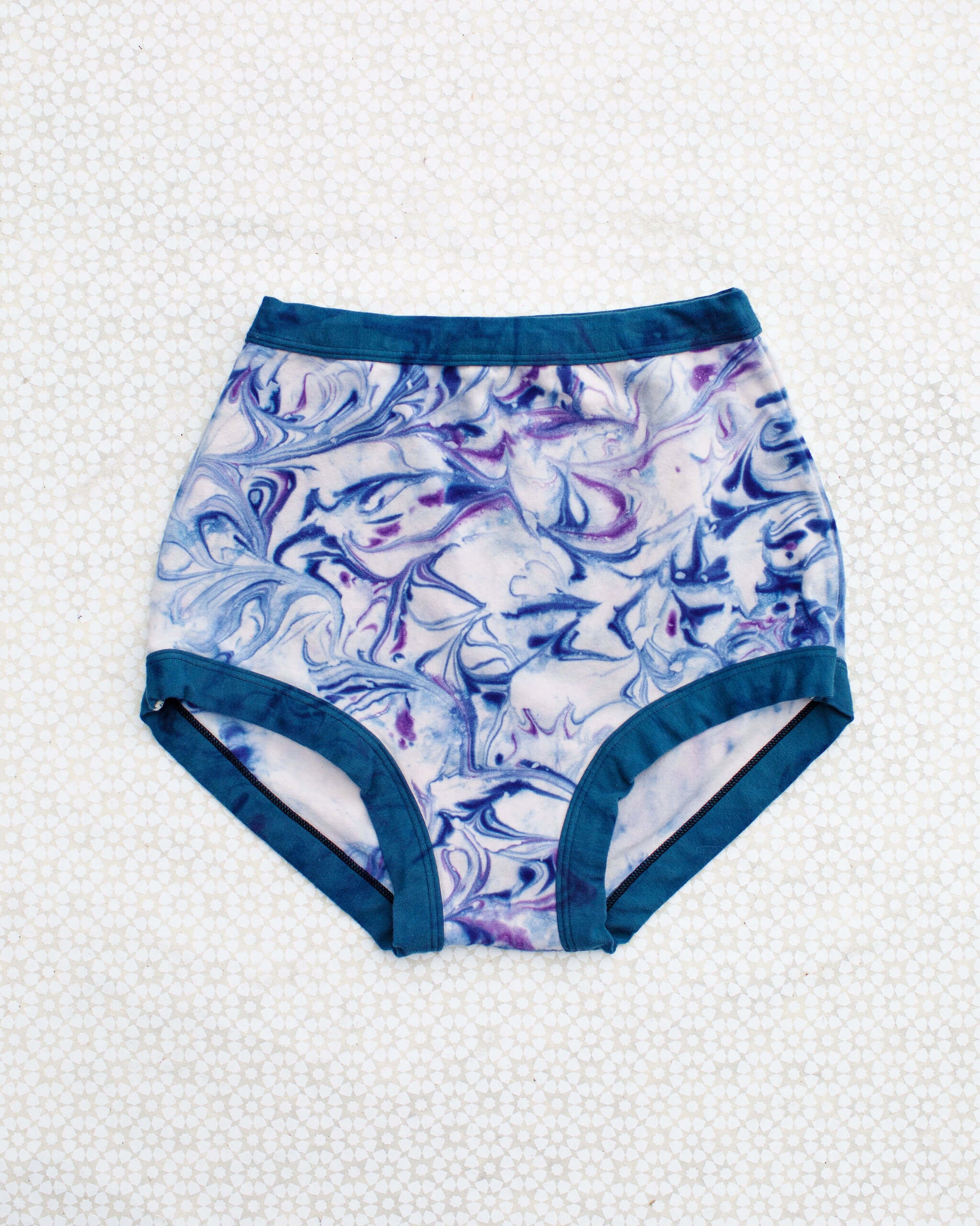 Flat lay of Thunderpants Sky Rise style underwear in Winter Blues Marble dye - different blues and purples swirled to look like marble. 