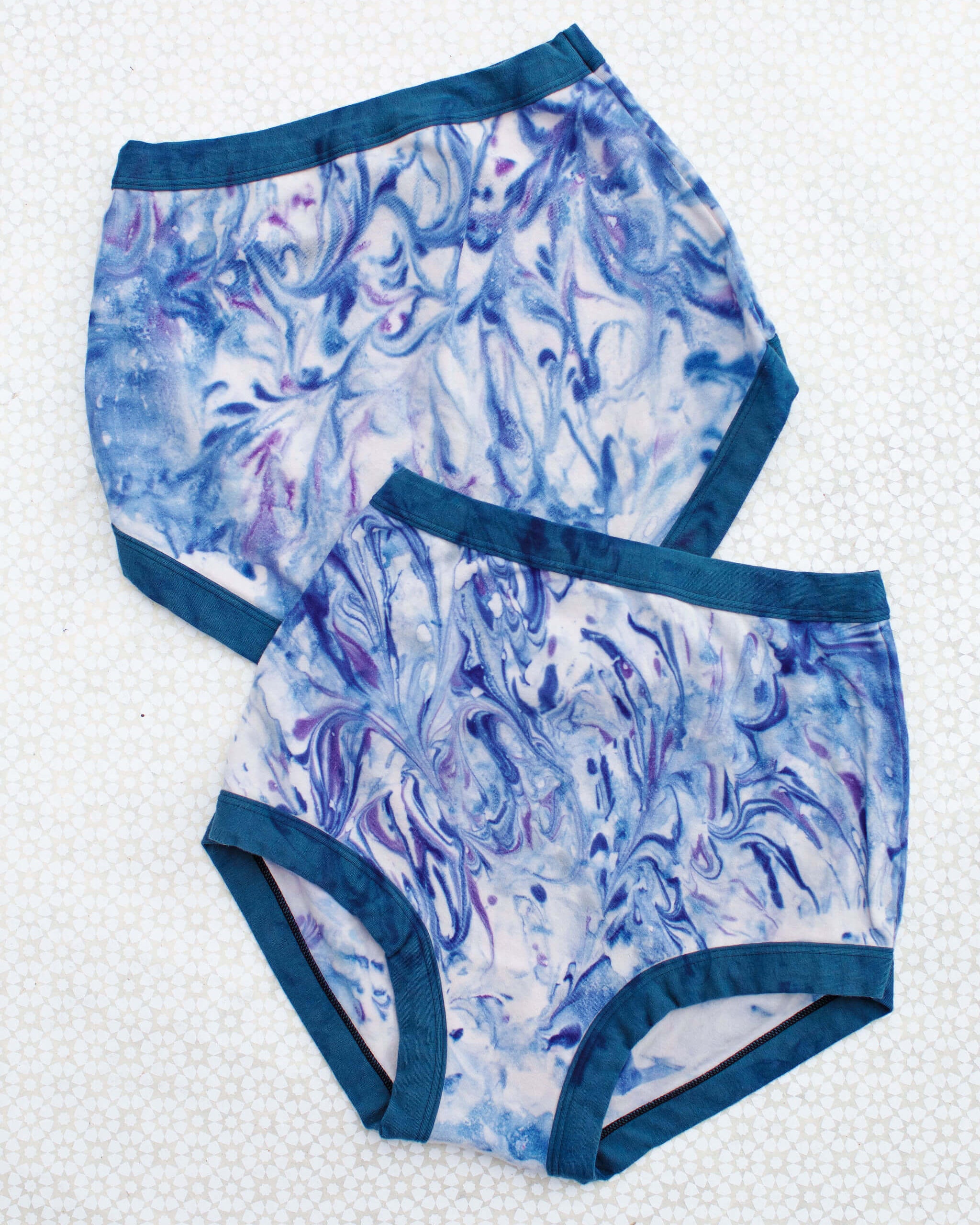 Flat Lay of Thunderpants Sky Rise style underwear in Winter Blues Marble dye - different blues and purples swirled to look like marble. 