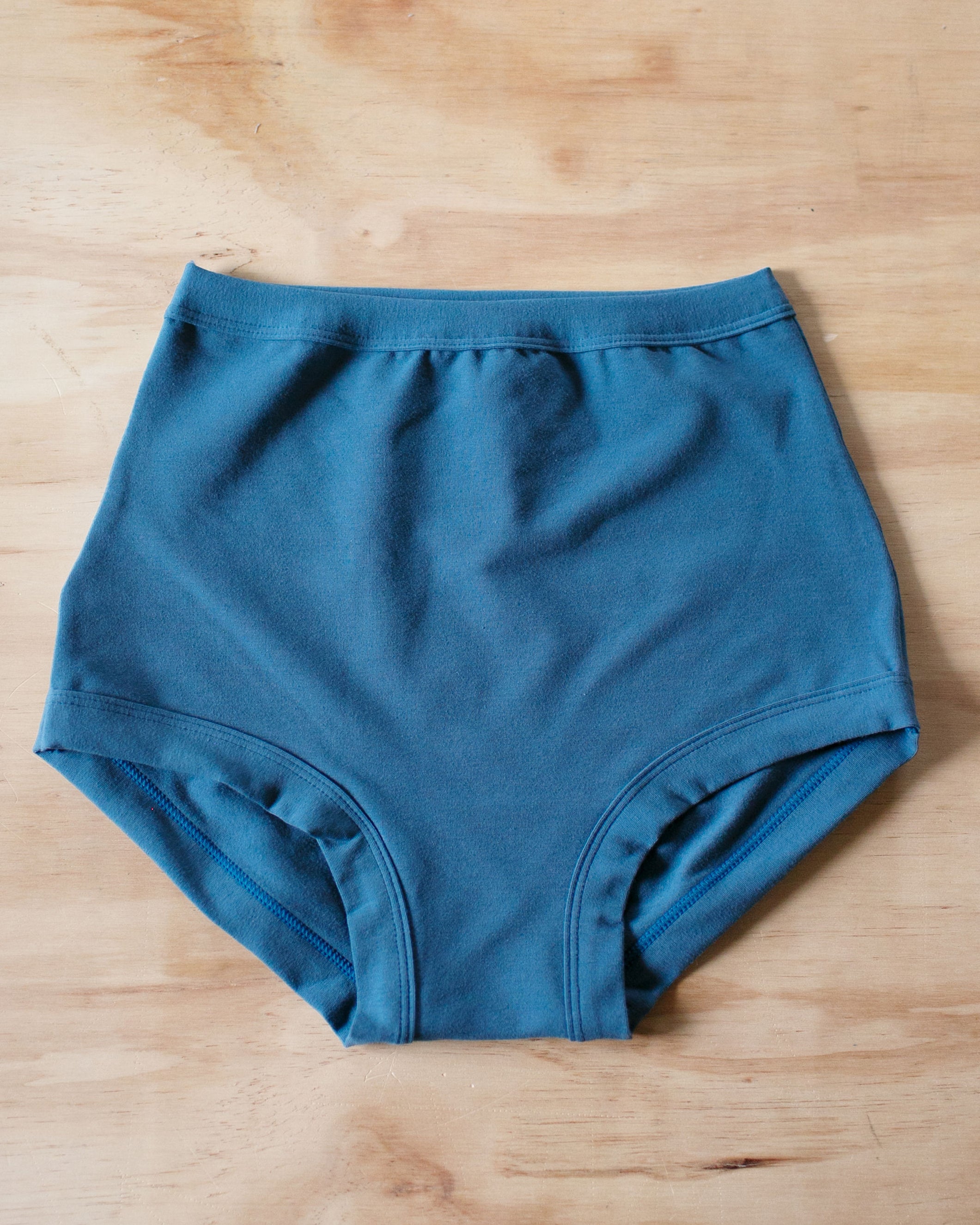Flat lay of Thunderpants organic cotton Sky Rise style underwear in Stormy Blue color.