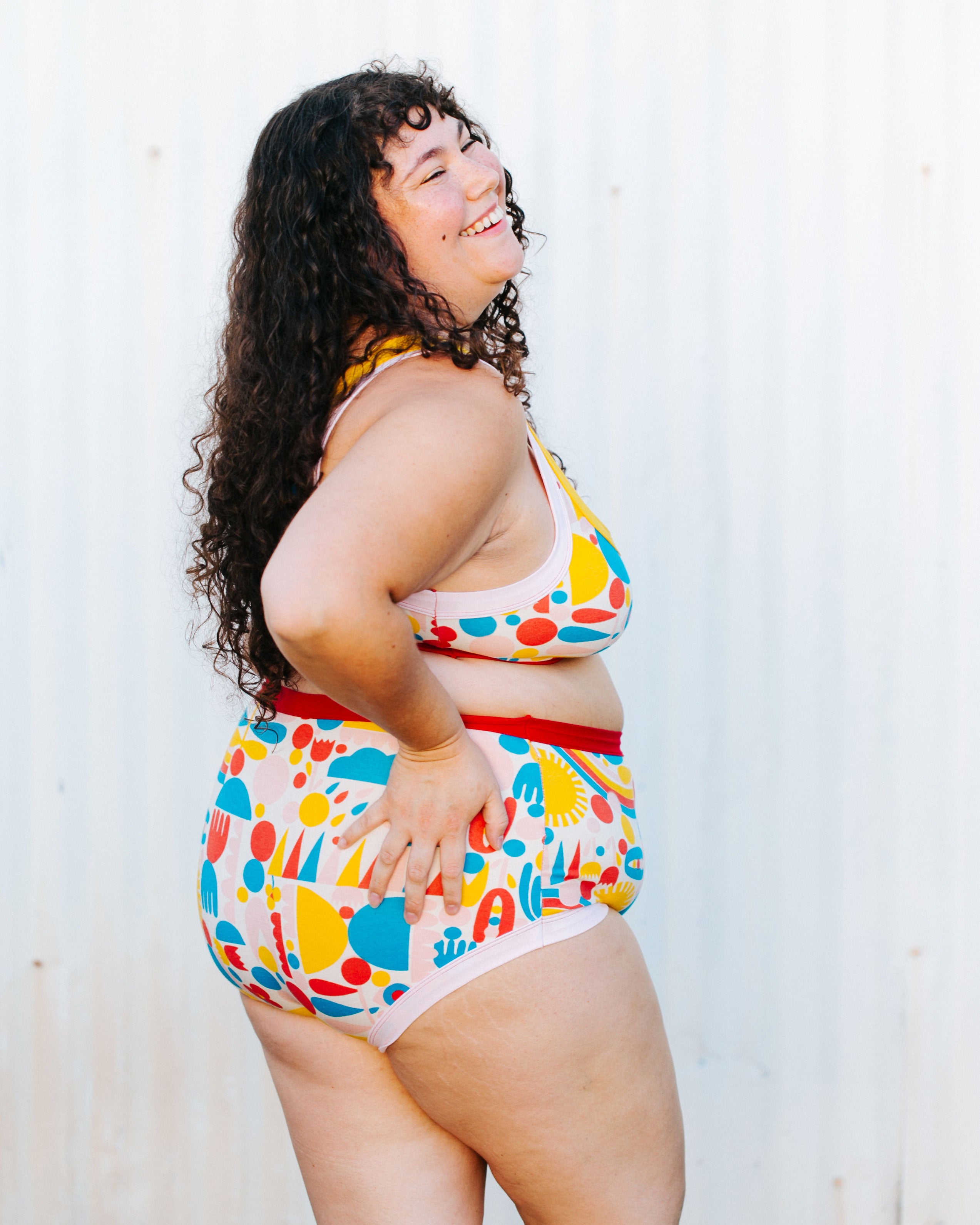 Model with her back to us wearing Original style underwear and Bralette in Balance by Lisa Congdon print: geometric shapes in pink, red, yellow, and blue colors.