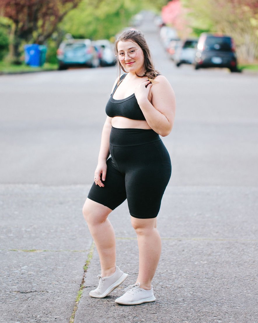 Woman standing in a street outside wearing Thunderpants organic cotton High Rise Bike Shorts and Bralette in plain black.