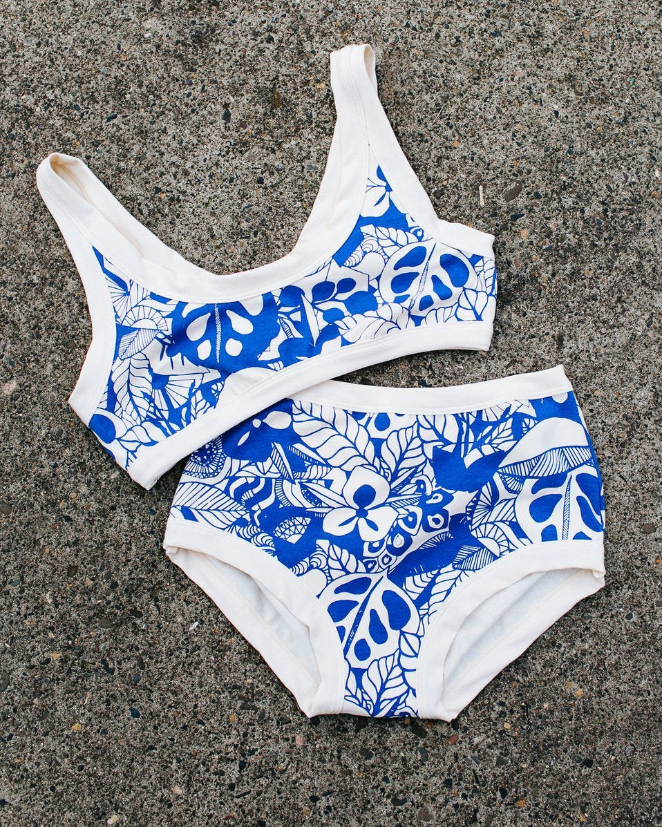 Flat lay of Thunderpants organic cotton Original style underwear and Bralette in a blue jungle and floral print.