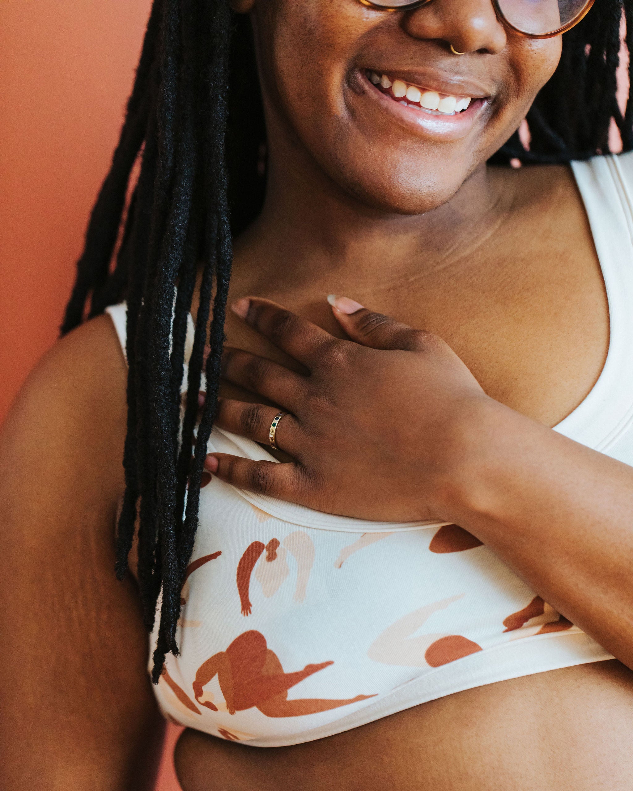 Close up of smiling model wearing Thunderpants Bralette in Bodies in Motion: women in different shades of tans and browns.