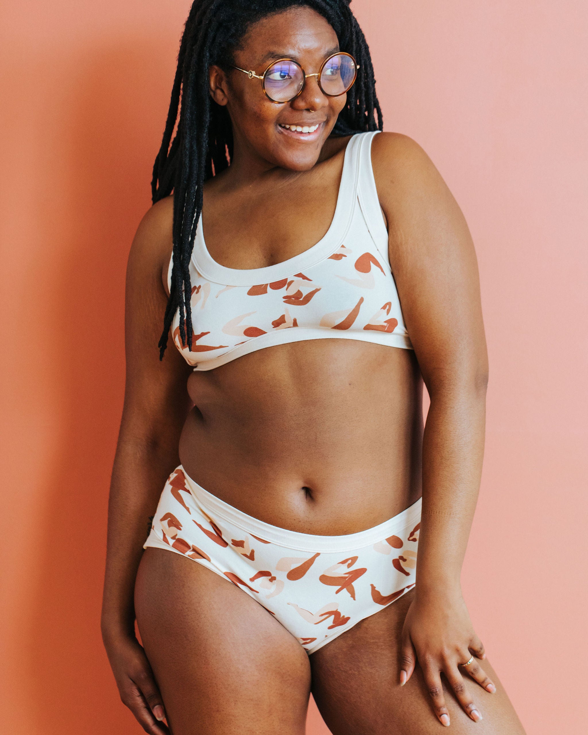 Model smiling wearing Thunderpants Hipster style underwear and Bralette in Bodies in Motion: women in different shades of browns and tans.