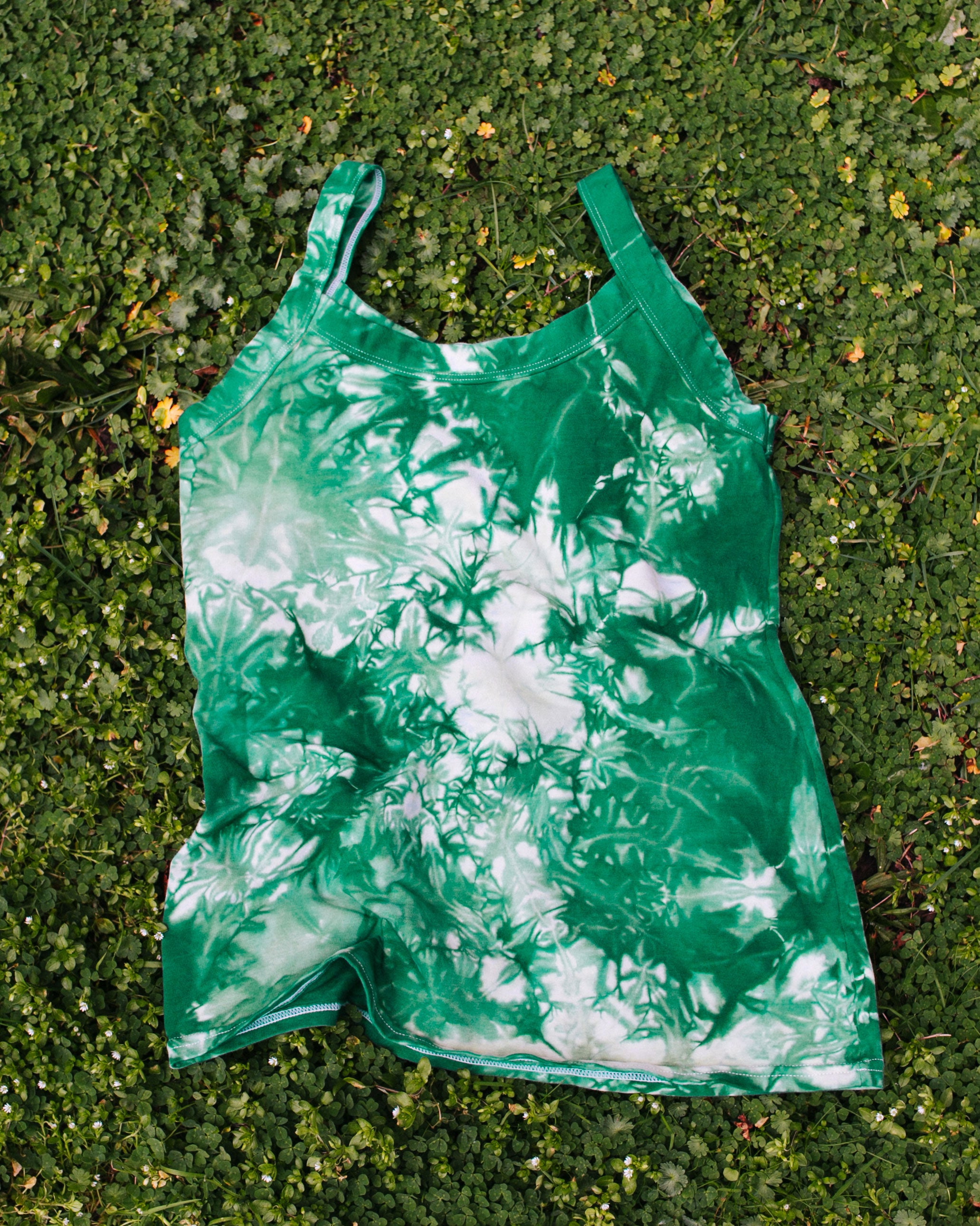 Flat lay on bright green clover grass of Thunderpants organic cotton Camisole in Clover Green scrunch dye.