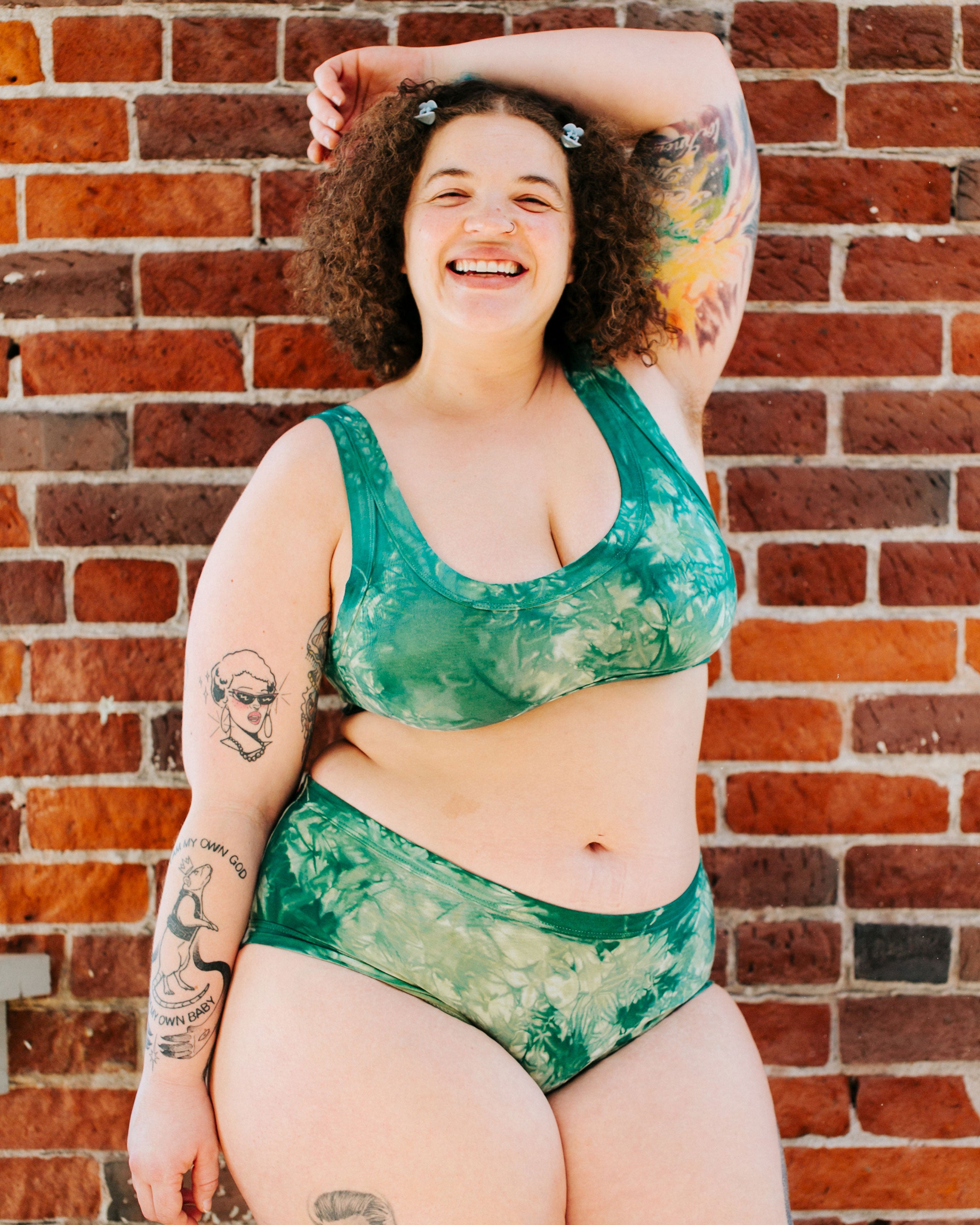 Model smiling while wearing Thunderpants organic cotton Hipster style underwear and Bralette in Clover Green scrunch dye.