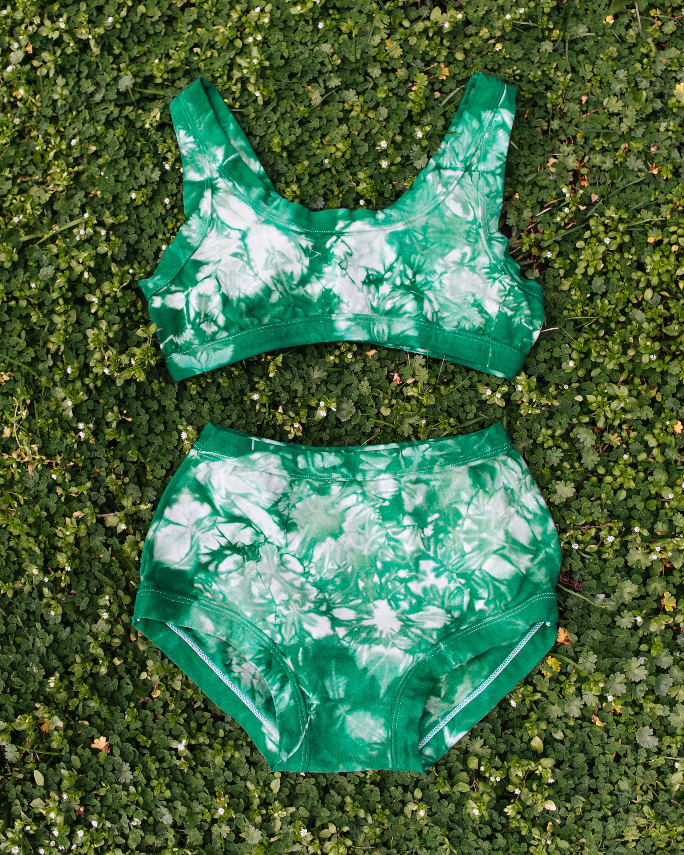 Flat lay of Thunderpants organic cotton Original style underwear and Bralette in Clover Green scrunch dye.
