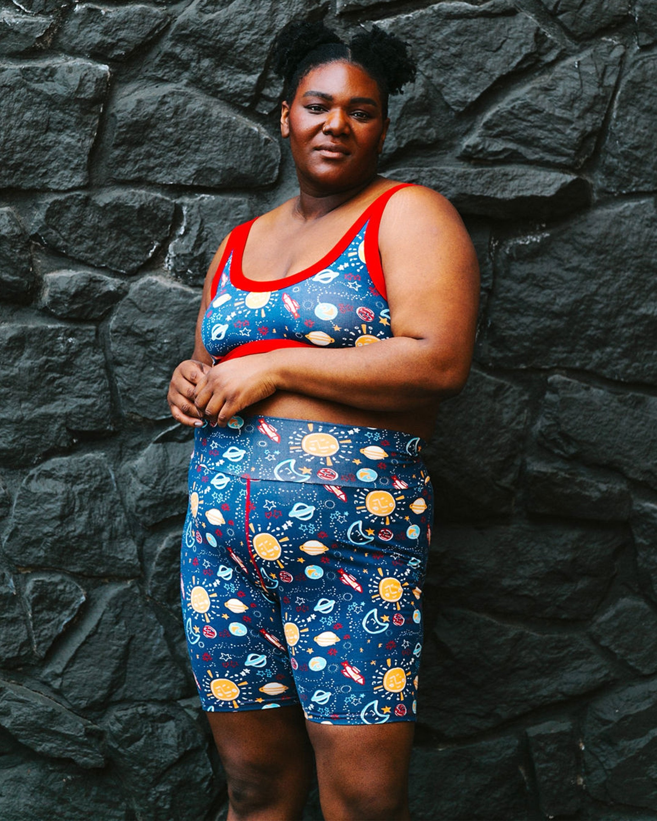 Beautiful plus-sized model wearing Thunderpants organic cotton High Rise Bike Shorts and Bralette in a sun, planet, stars, and universe print.