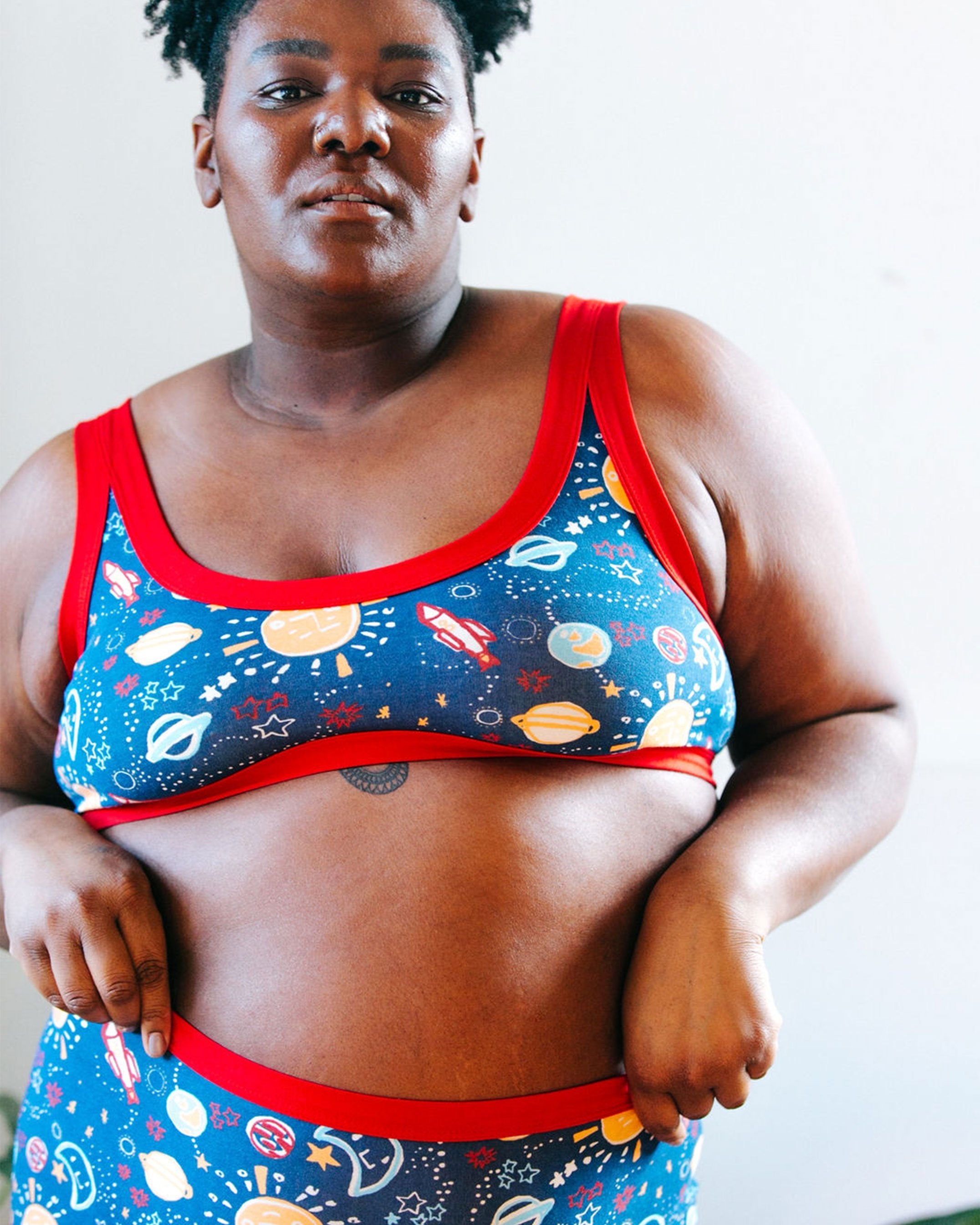 Close-up of a beautiful plus-sized model wearing Thunderpants organic cotton Bralette and Original style underwear in sun, planet, stars, and universe print.