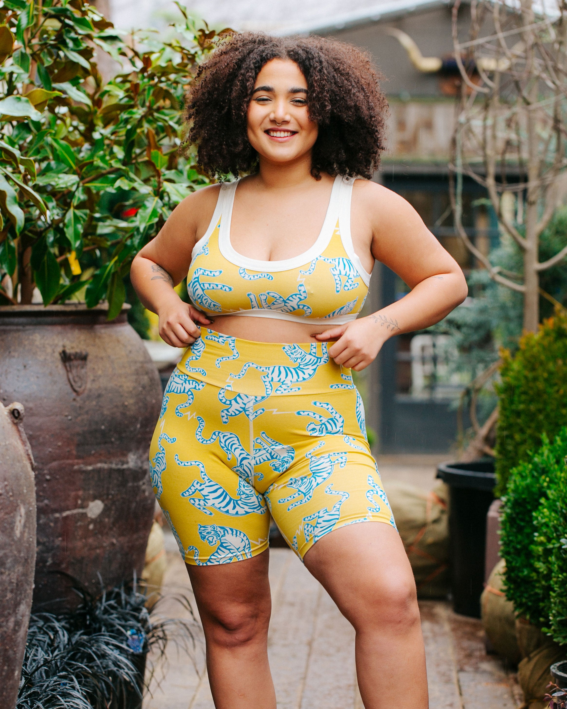 Model smiling while wearing Thunderpants organic cotton Bike Shorts and Bralette in Easy Tiger - chartreuse with blue and white tigers.