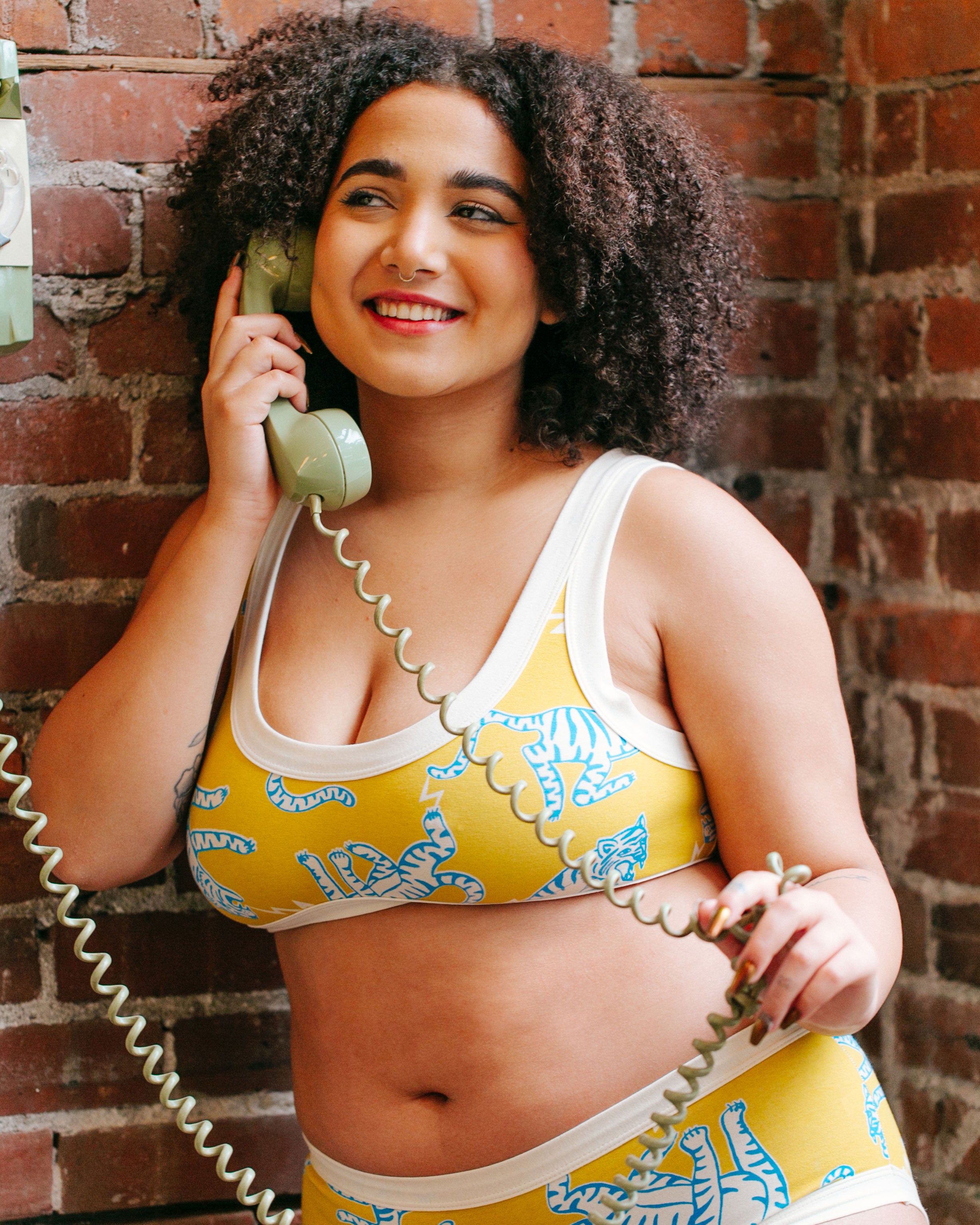 Model smiling while wearing Thunderpants organic cotton Bralette in Easy Tiger - chartreuse with blue and white tigers.