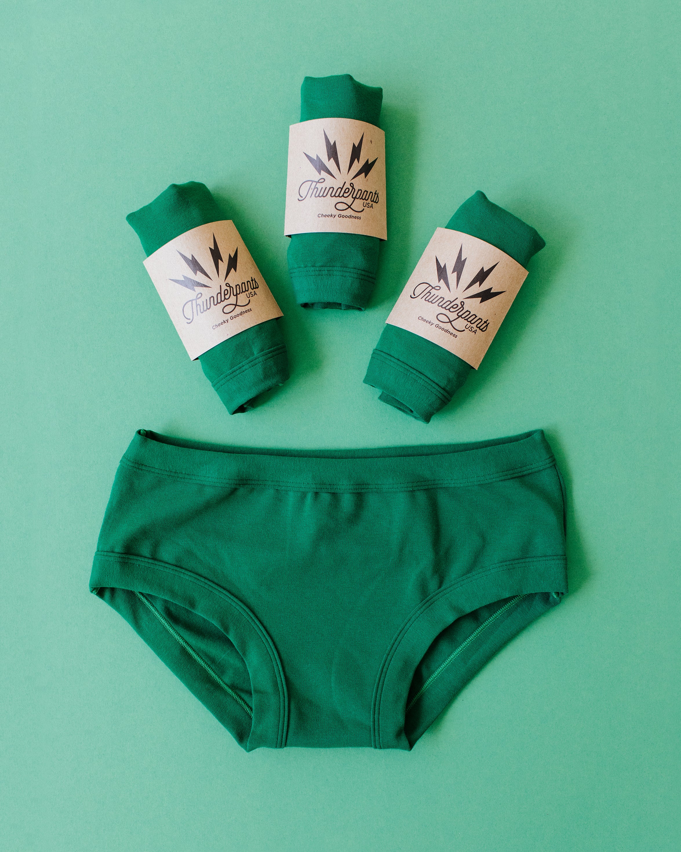 Flat lay of Thunderpants Hipster style underwear and three packaged undies in Emerald Green.