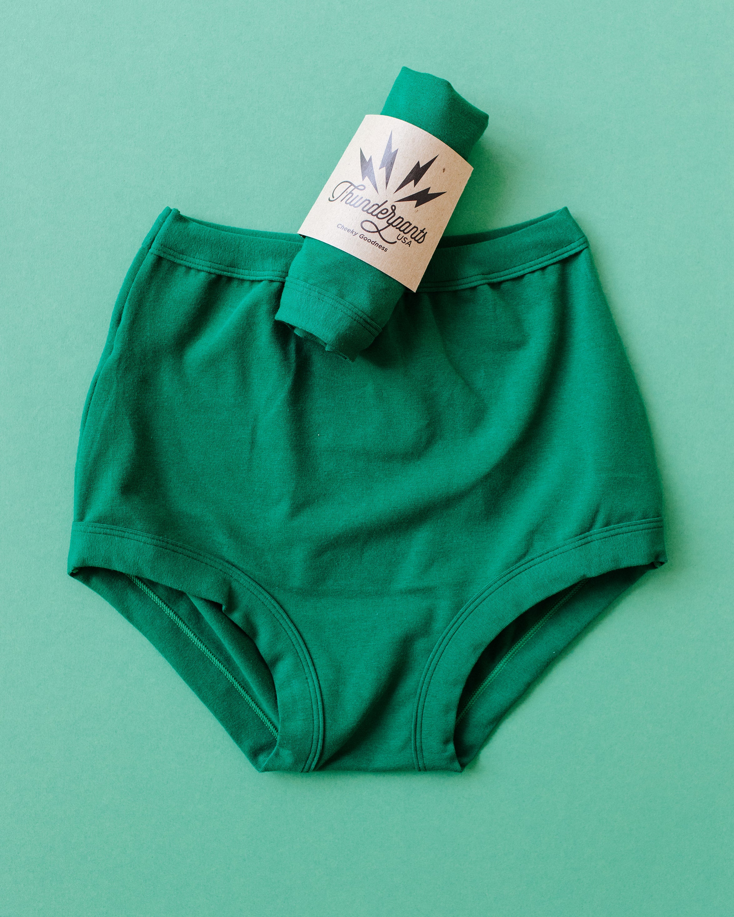 Flat lay of Thunderpants Sky Rise style underwear and a packaged pair in Emerald Green.