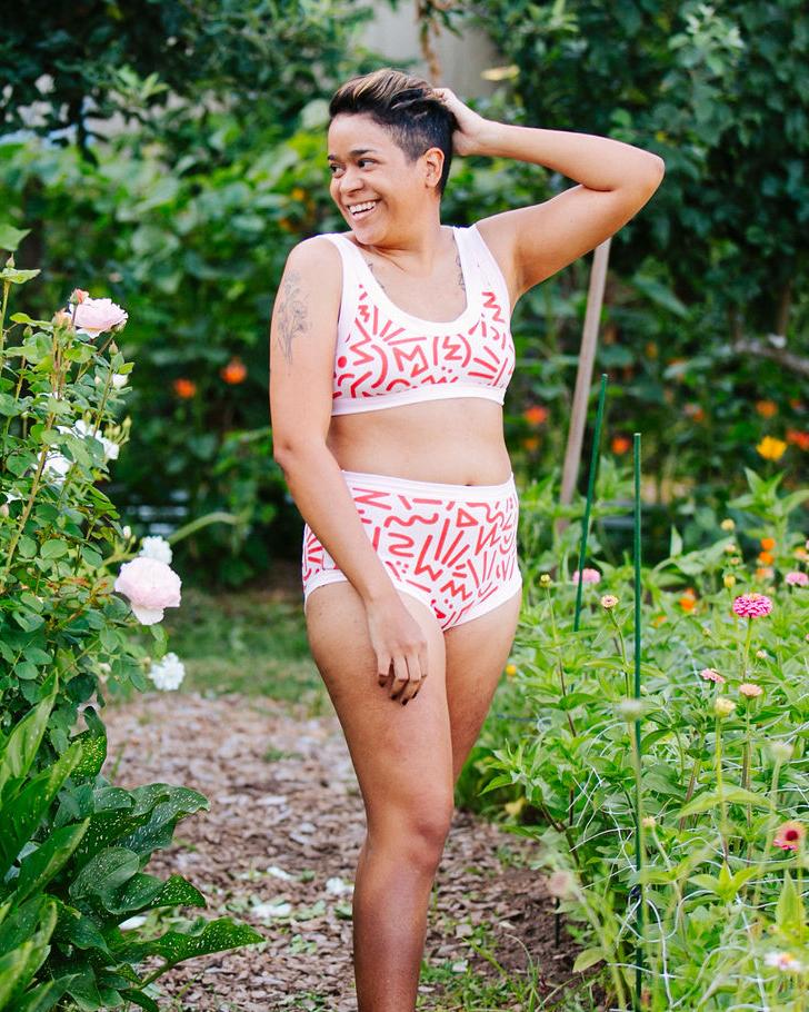 Model smiling outside wearing Thunderpants Organic Cotton Bralette and Original style underwear in our Energy Vibes print: Perfect Pink with dark pink large squiggles.