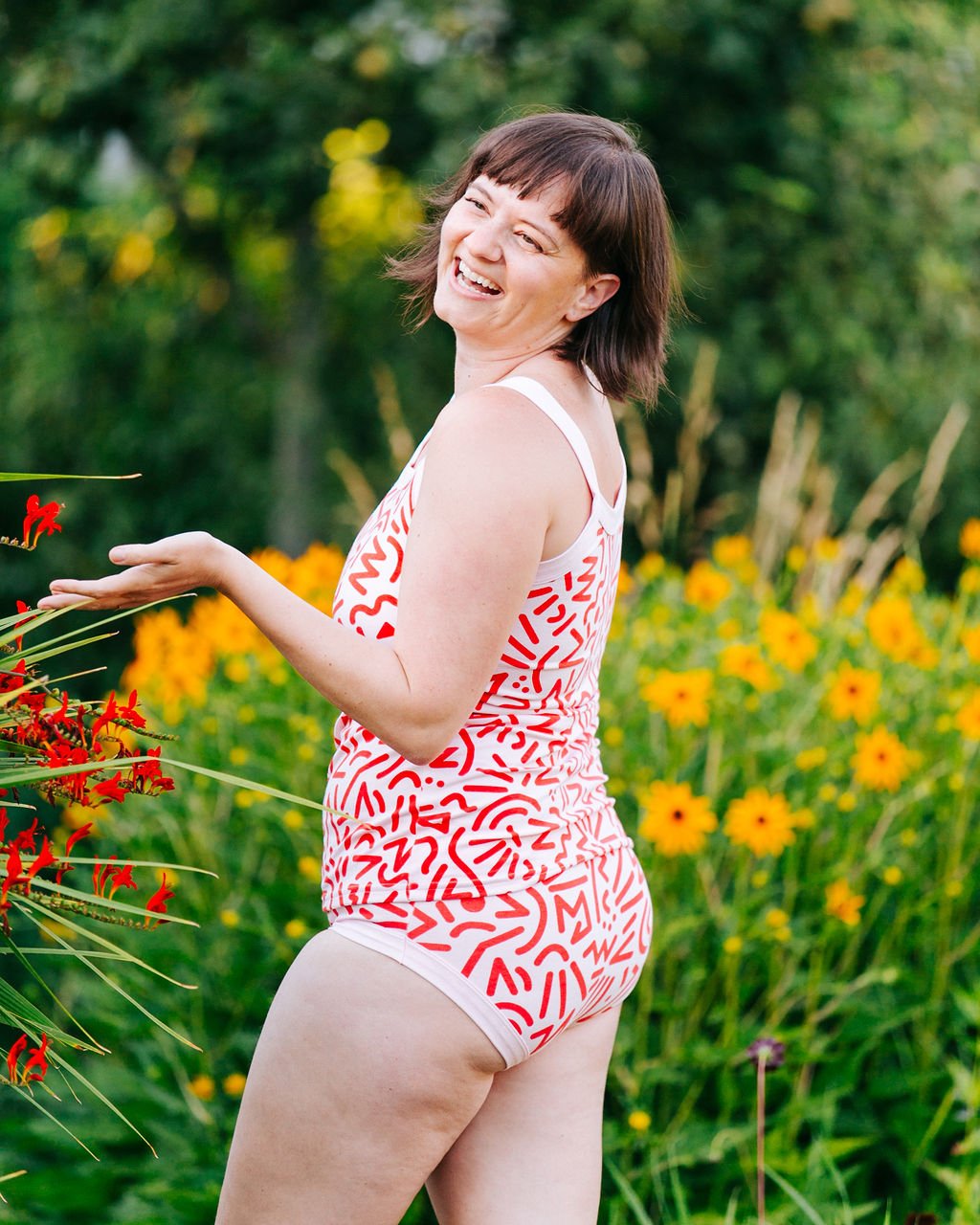 Model smiling outside from the back wearing Thunderpants organic cotton Hipster style underwear and Camisole in our Energy Vibes print: Perfect Pink with dark pink large squiggles.