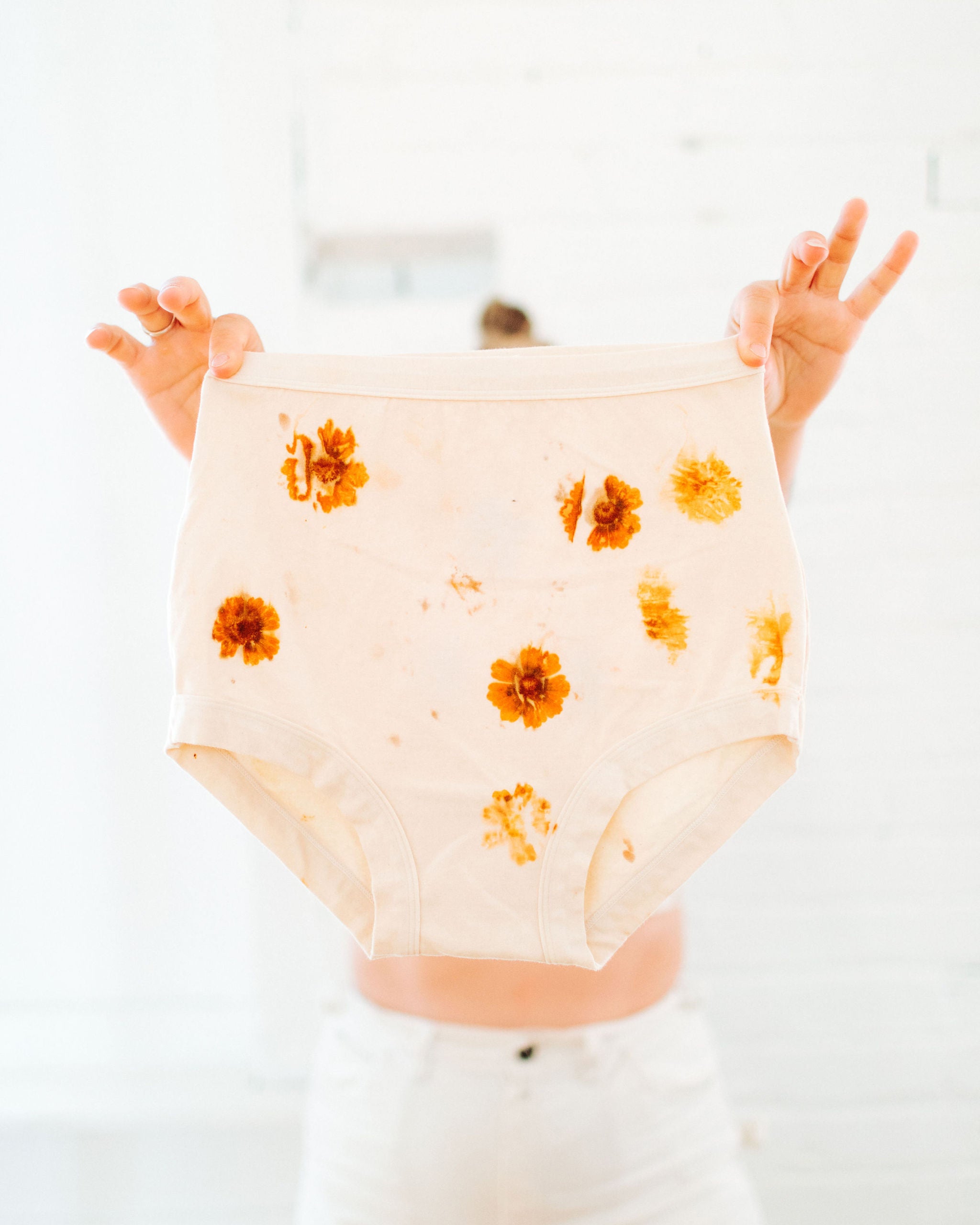 Person holding Thunderpants Sky Rise style underwear in the Limited Edition Flower Press Botanical Dye - flowers pressed on the underwear to create a print.