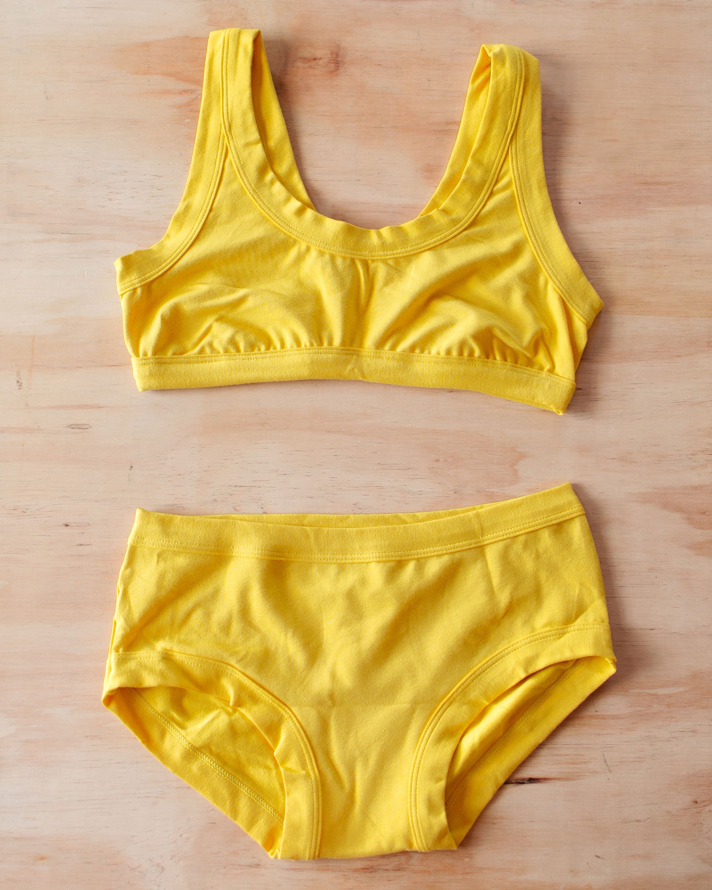 Flat lay of Thunderpants Organic Cotton Bralette and Hipster style underwear in Golden Yellow color.