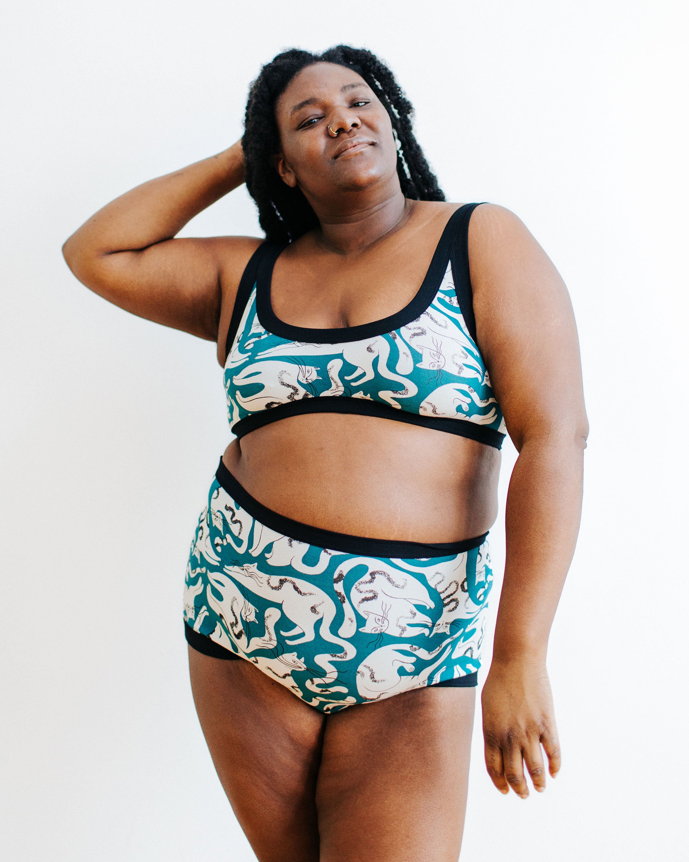 A model wearing a Bralette and Sky Rise set in Hey Meow! print - green with white cats.