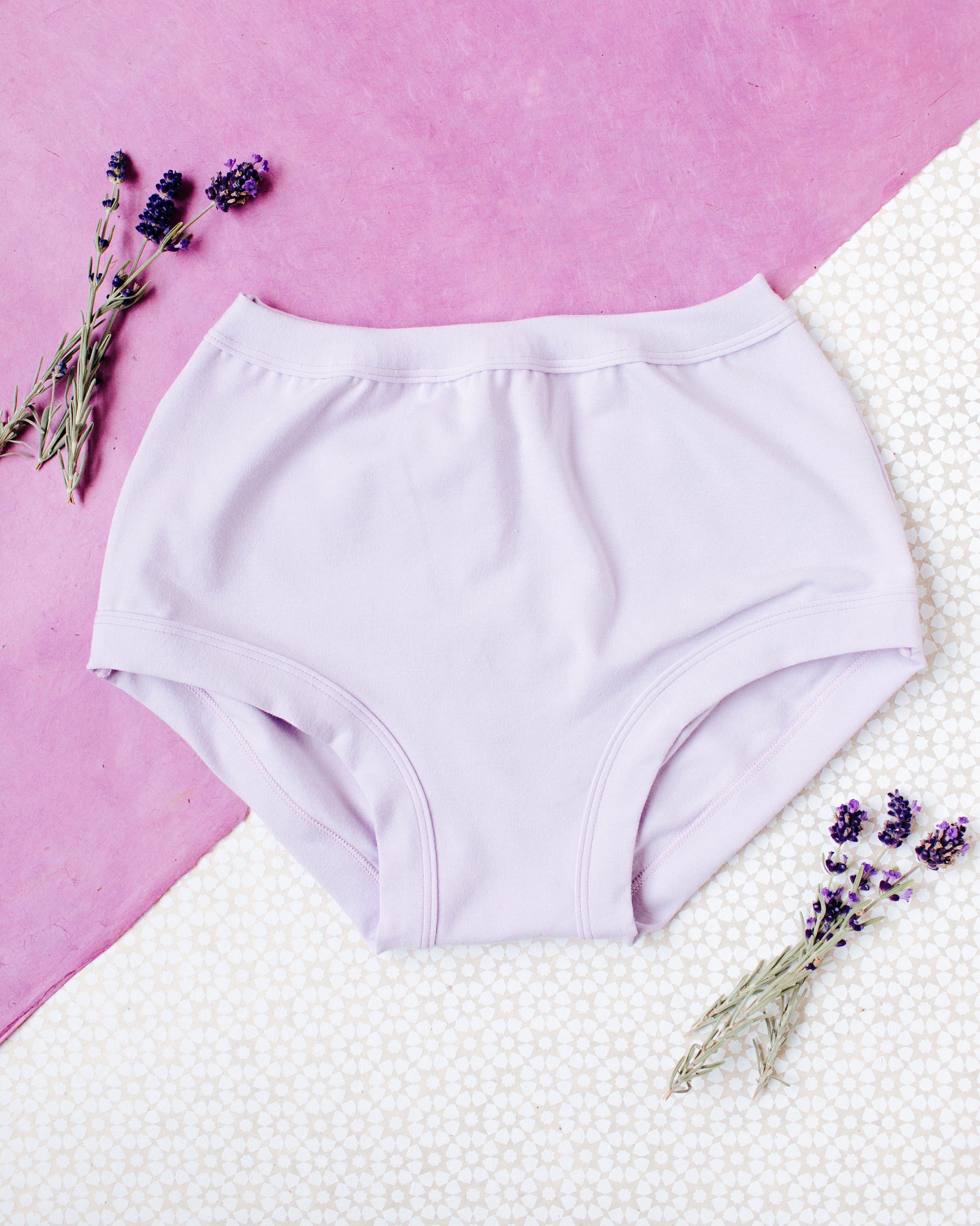 Flat lay of Light Lavender in Original style underwear on a purple and white patterned surface with lavender sprigs.