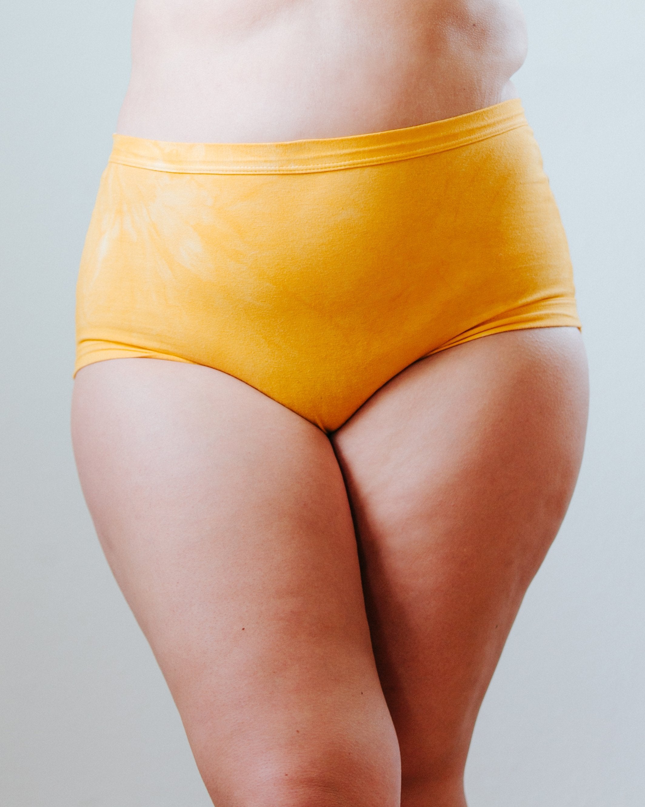 Front of a plus-size woman wearing Thunderpants organic cotton Women’s Original style underwear in limited edition hand dye marigold color.