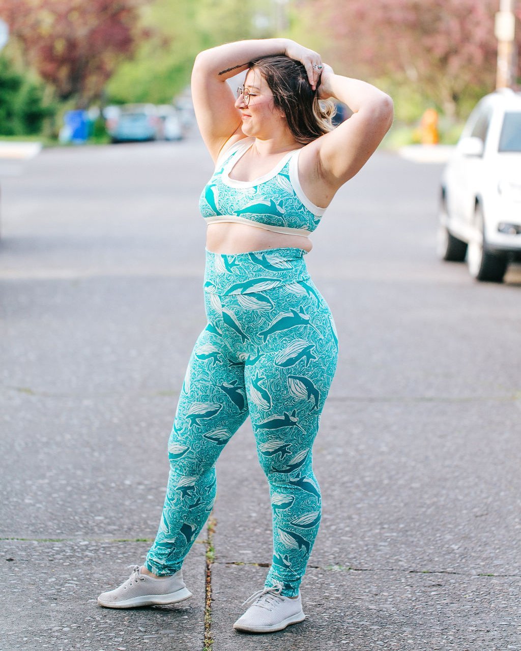 Woman standing in the street outside wearing Thunderpants organic cotton High Rise Extra Long Length Leggings and Bralette in a teal whales print.