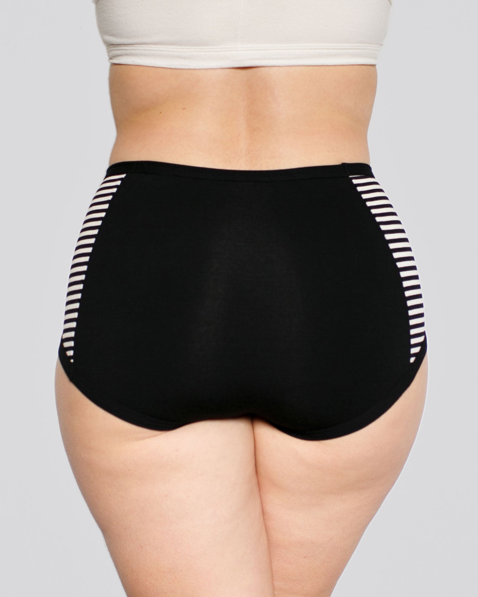 Model from the back wearing Thunderpants organic cotton Original Panel Pant style underwear with plain black center and black and white stripe sides.