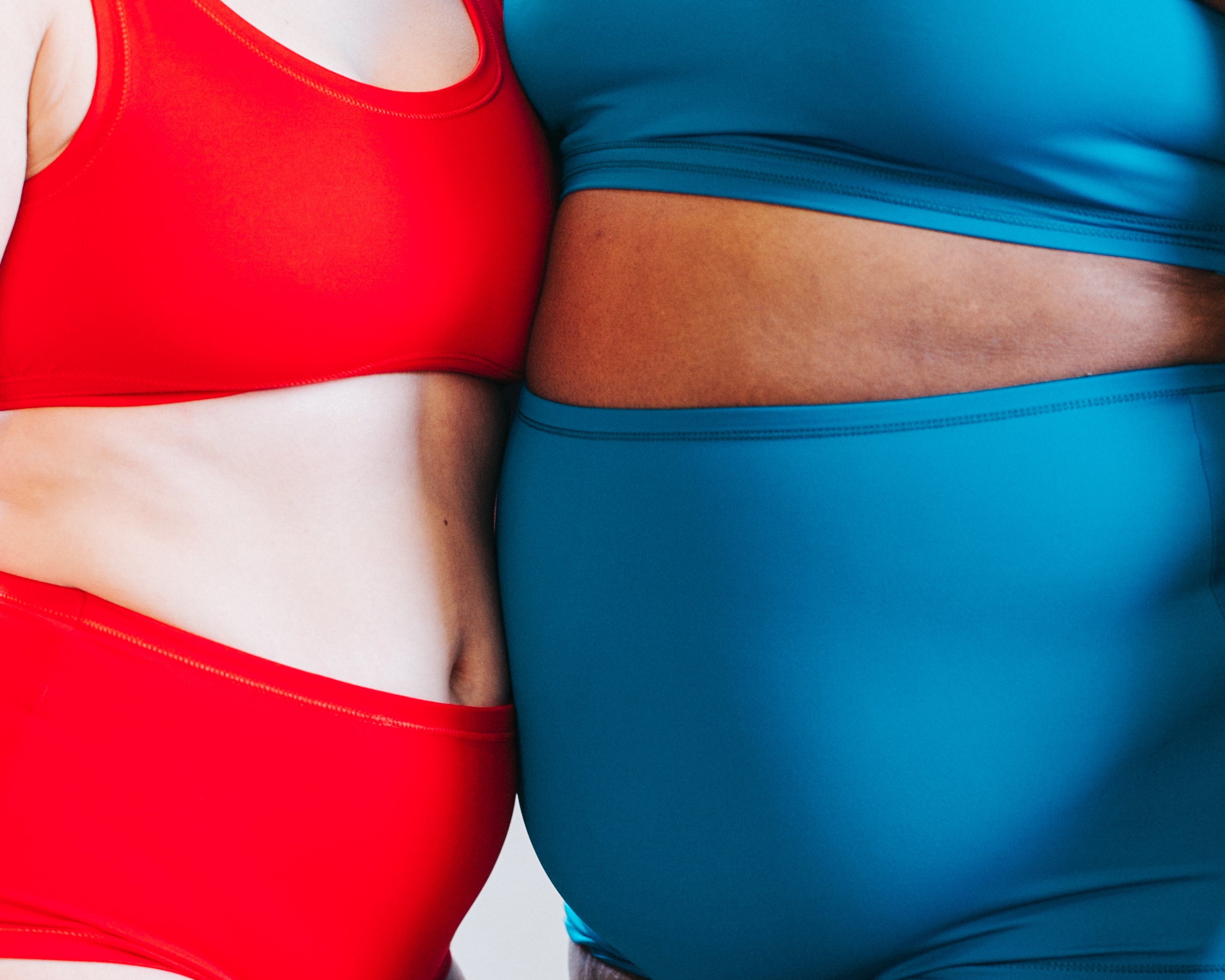Close up of models standing together wearing Classic Red and Marina Blue Swimwear sets.
