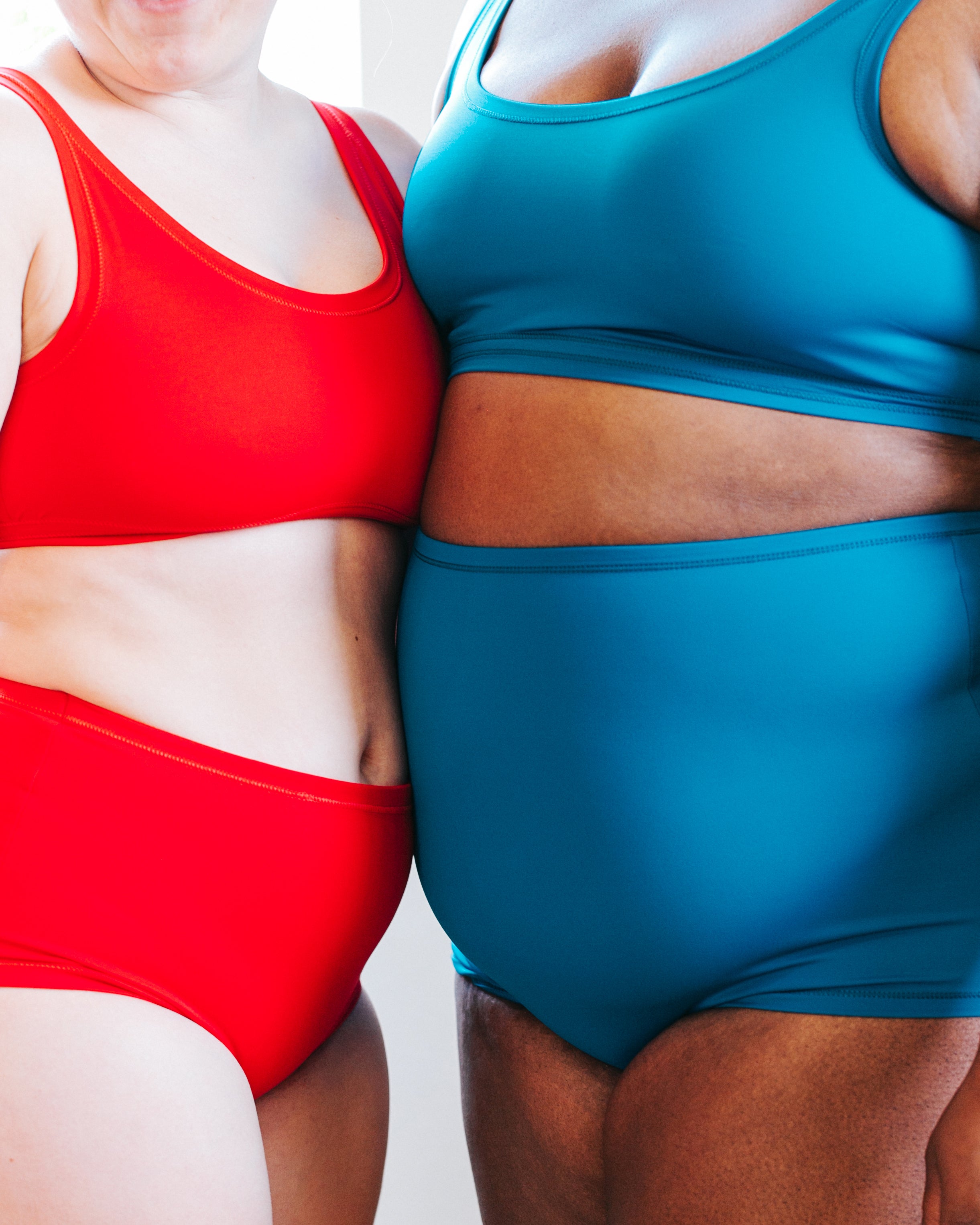 Close up of models standing together wearing Classic Red and Marina Blue Swimwear sets.