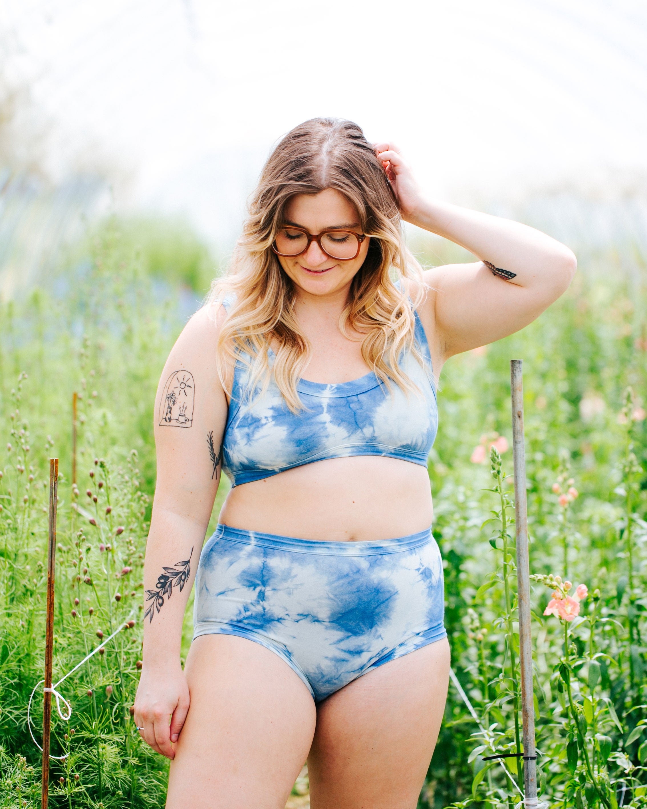 Model standing in a greenhouse wearing a set of indigo dyed Sauvie Skies Original style underwear and Bralette