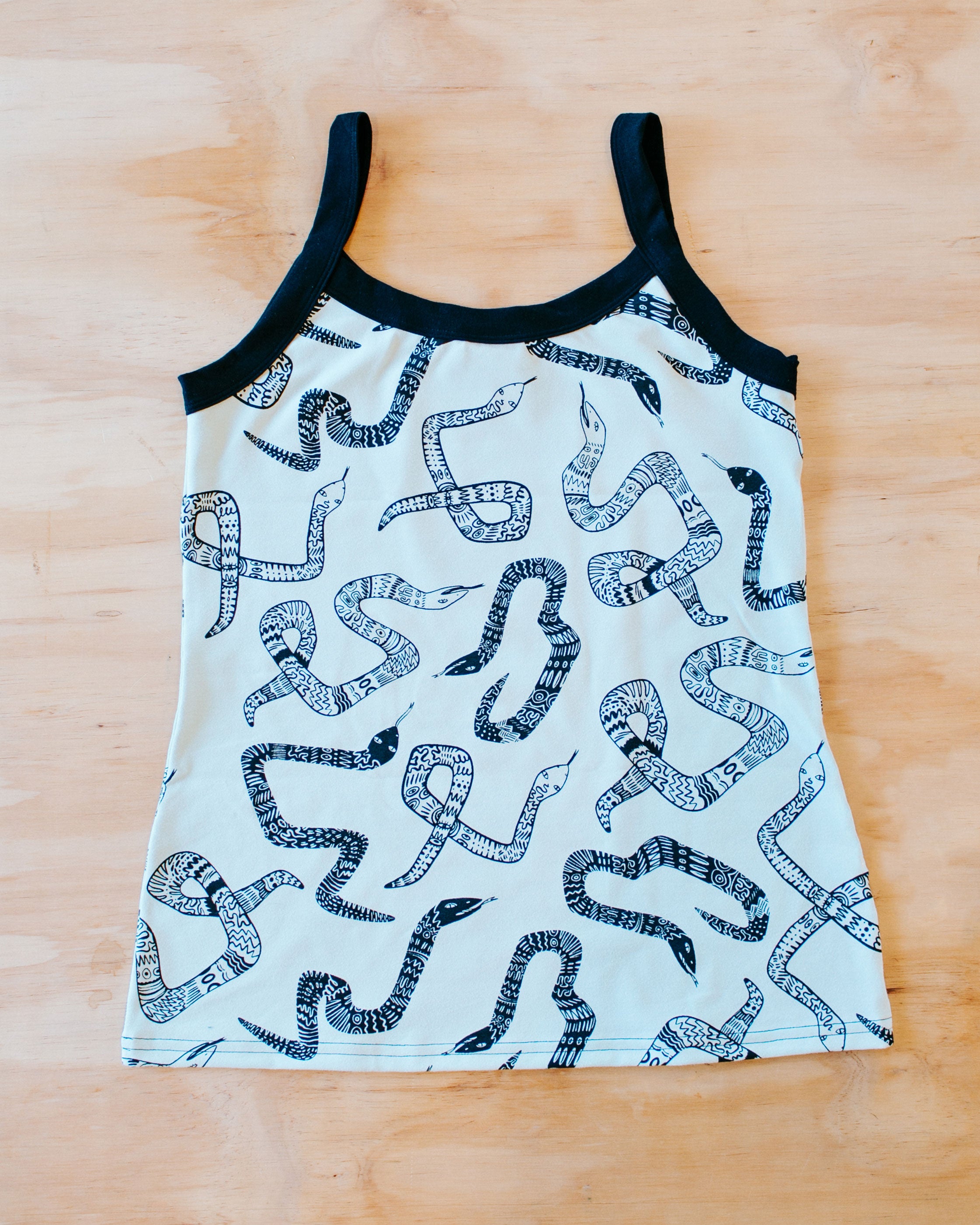 Flat lay of our Camisole in the Sketchy Snake pattern: dried sage color with black snakes and black binding.