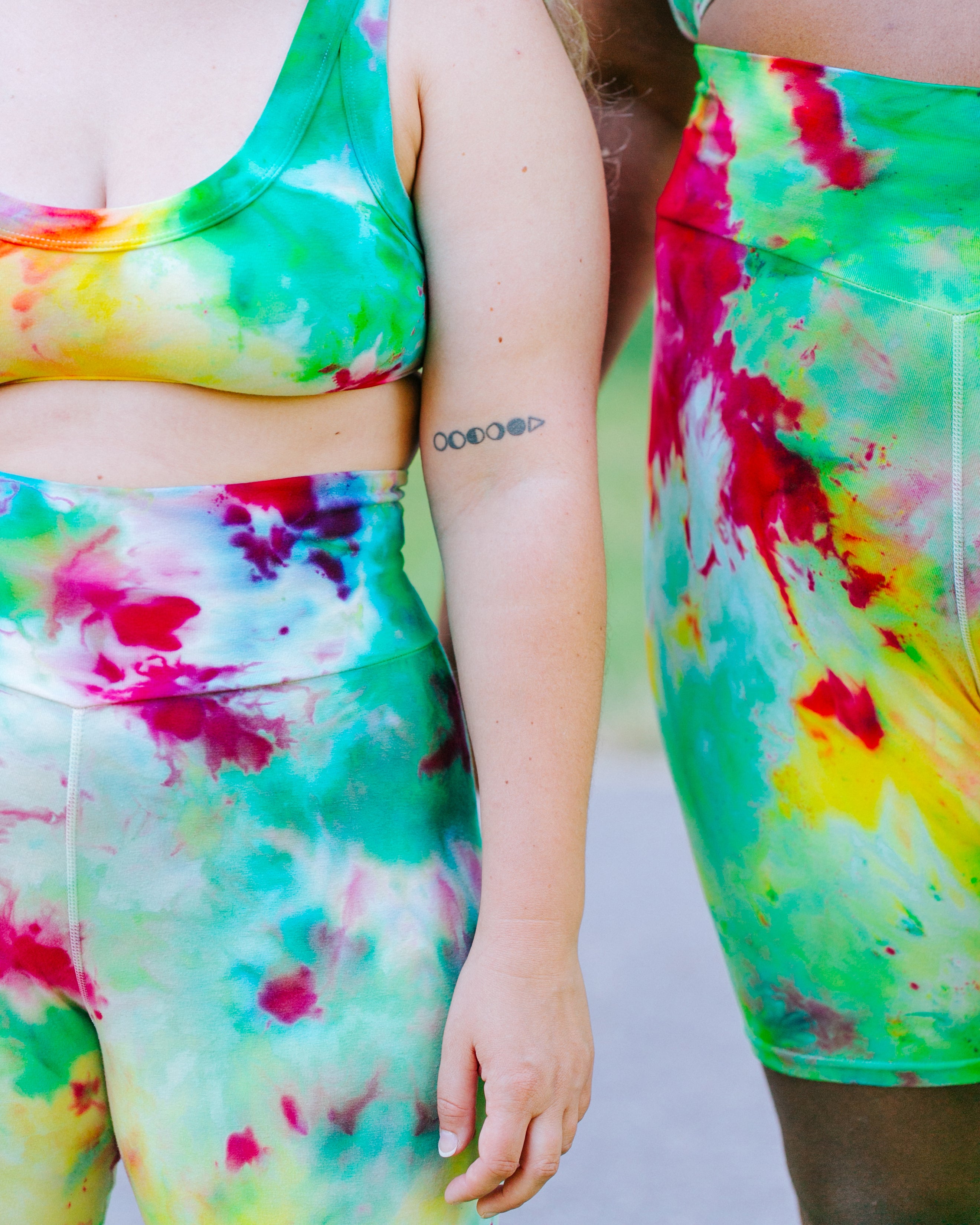 Close up of models wearing Ice Dyed Bike Shorts and Bralettes in a mix of green, pink, and yellow colors.