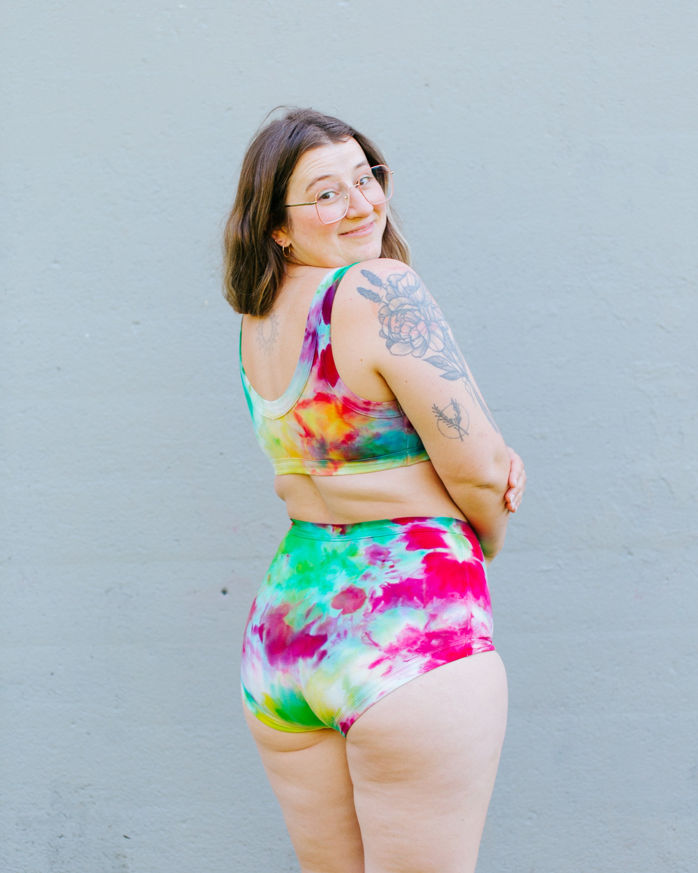Model with her back to us wearing a set of Ice Dyed Original style underwear and Bralette in a mix of pink, green, and yellow colors.