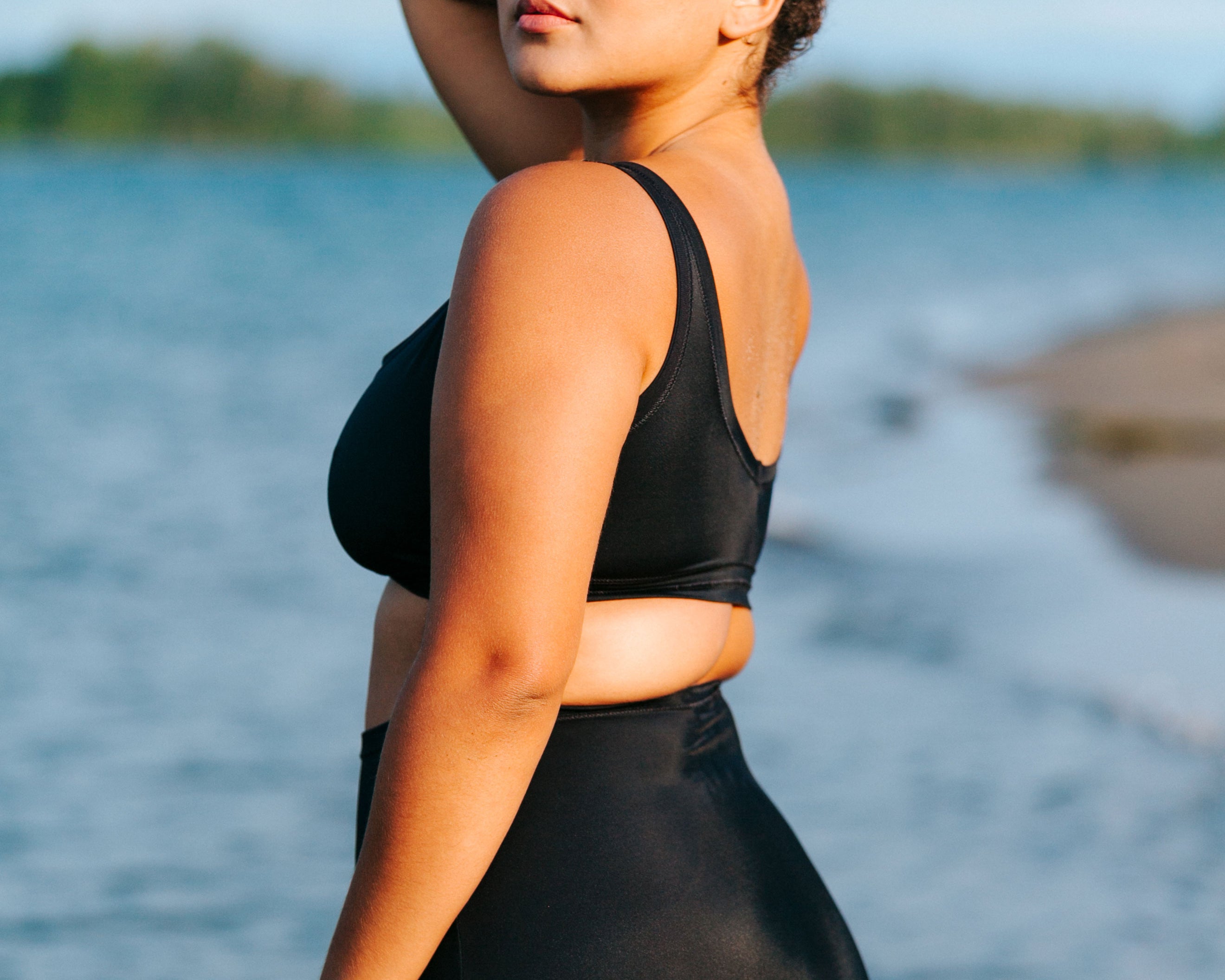 Model standing in the water with back to us wearing Thunderpants recycled nylon Sky Rise style Swimwear Bottoms and Swimwear Top in Plain Black.