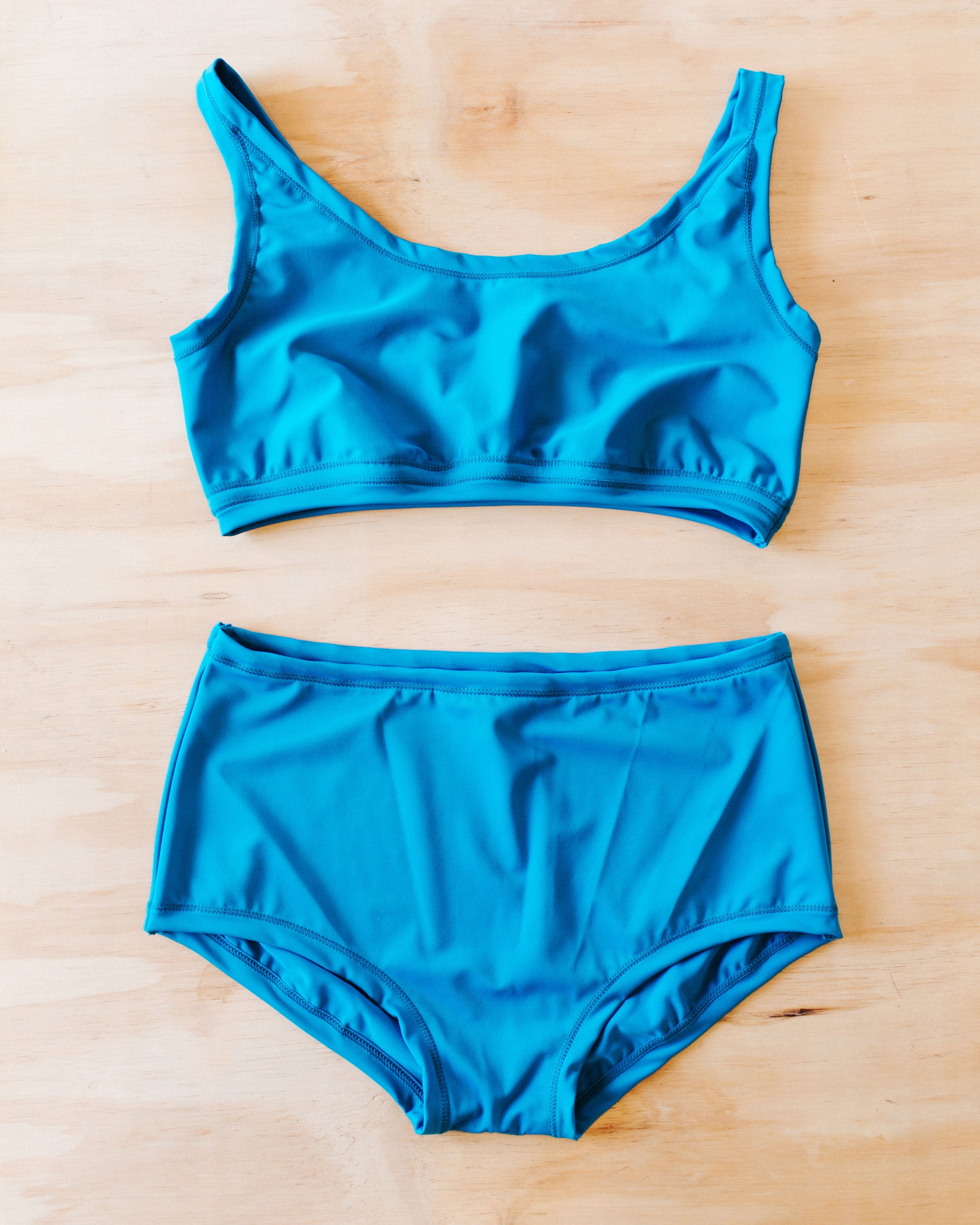 Flat lay on wood surface of Swimwear set with Original style bottoms and top in Marina Blue.