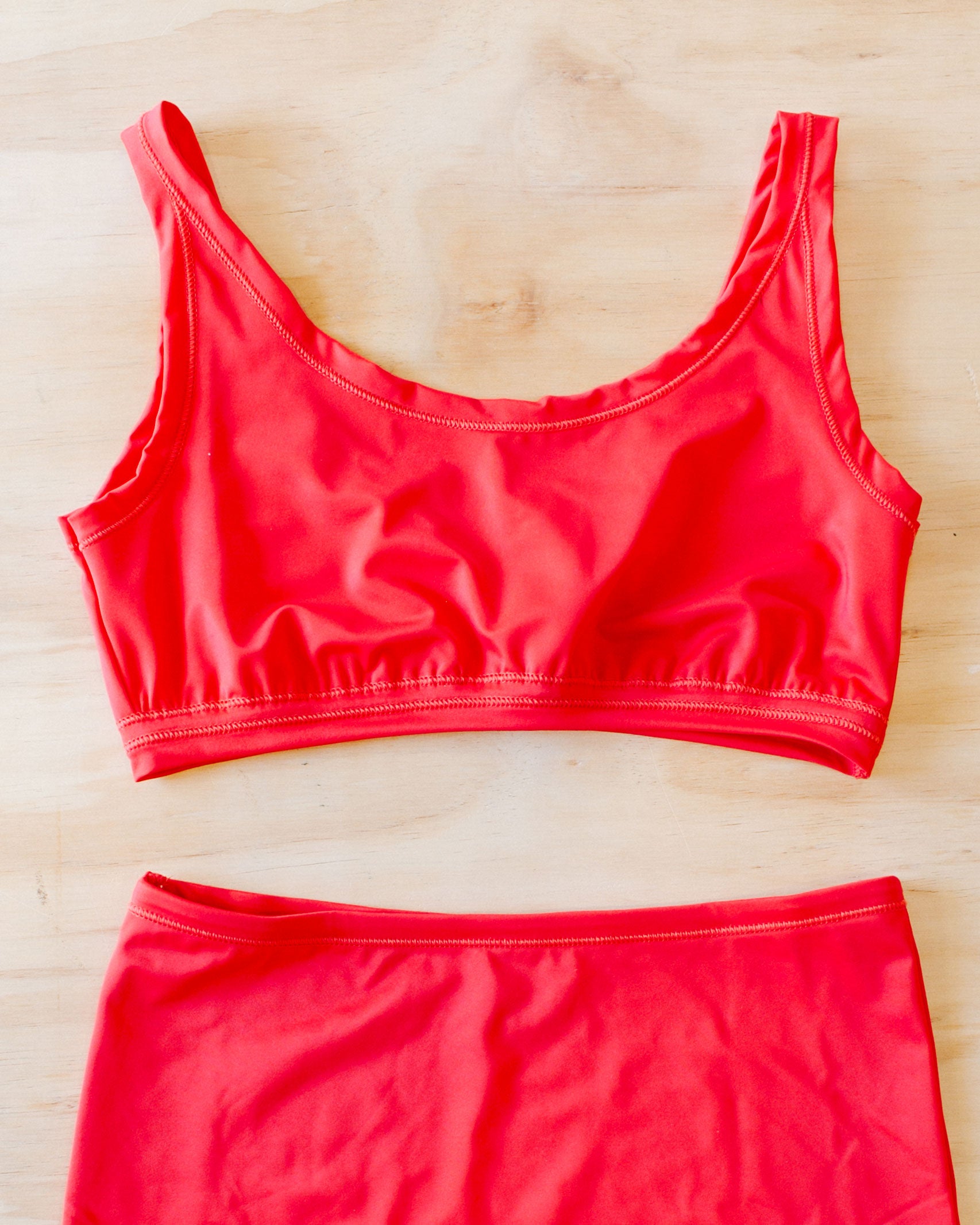 Flat lay on wood surface of Classic Red Swimwear top.
