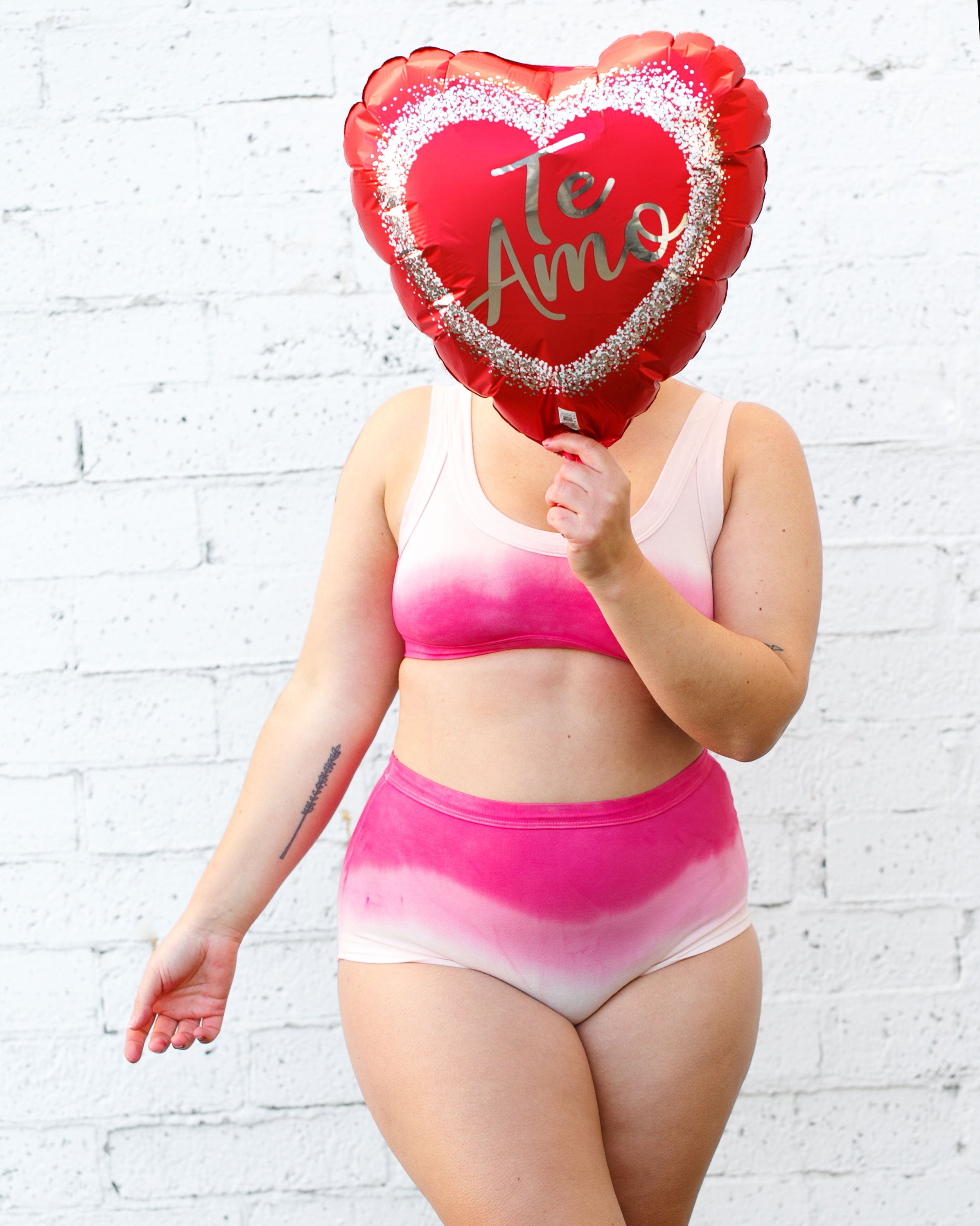Model wearing Thunderpants organic cotton Bralette and Original underwear in Valentine's Day Dip Dye ombre pinks with a heart balloon over the face.