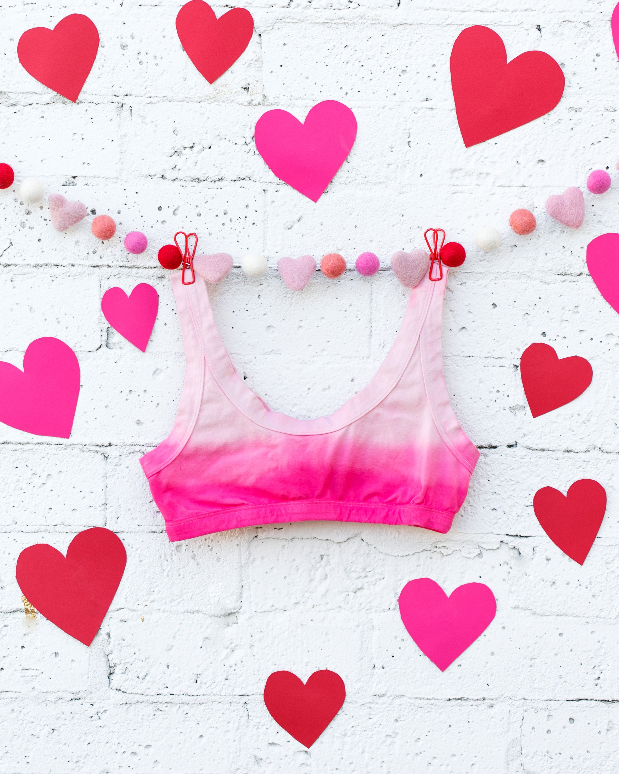 Photo of Thunderpants Organic Cotton bralette in hand dyed Valentine's Day Dip Dye with hearts around.