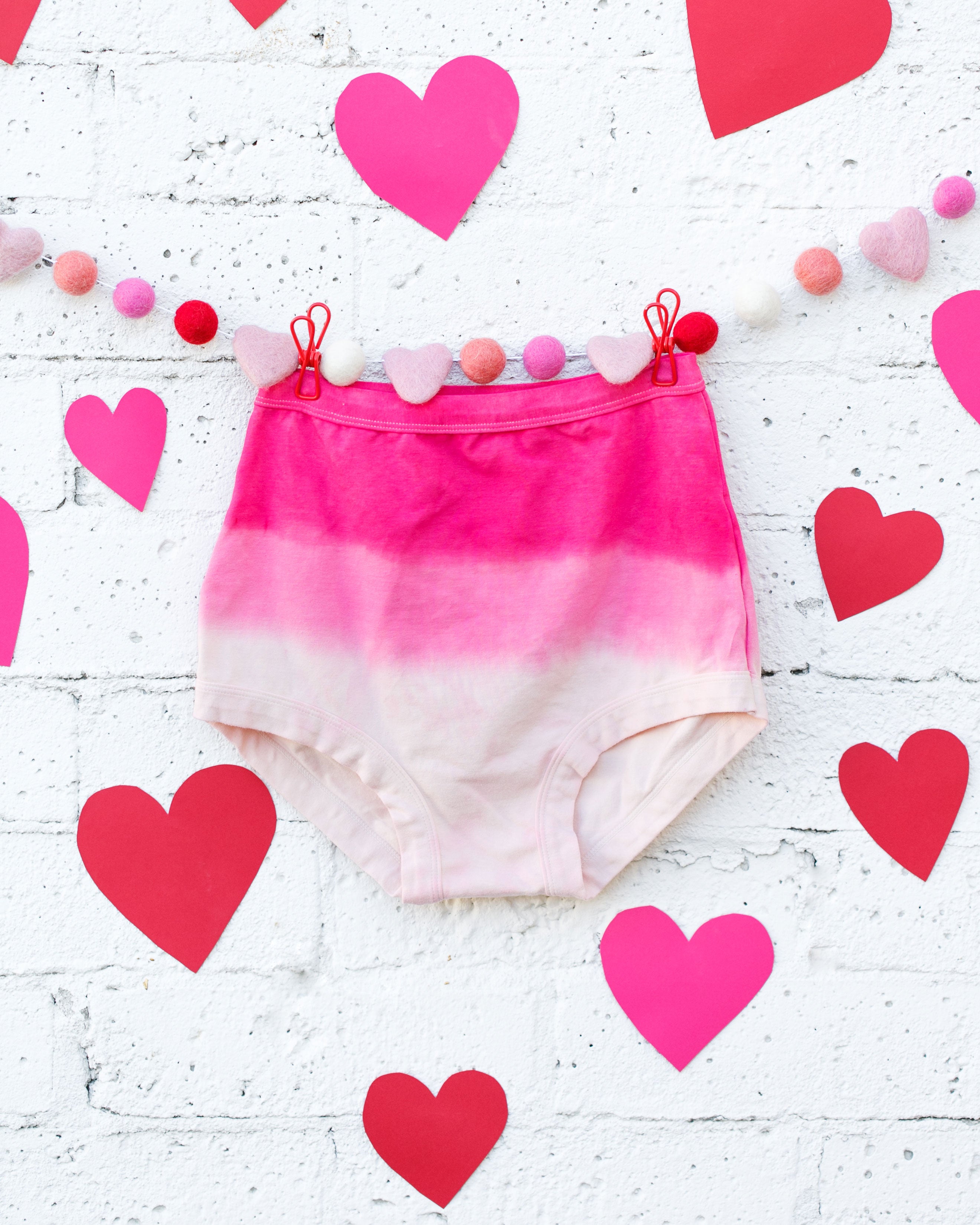 Photo of Thunderpants organic cotton Sky Rise underwear in Valentine's Day Dip Dye ombre pinks with hearts around.